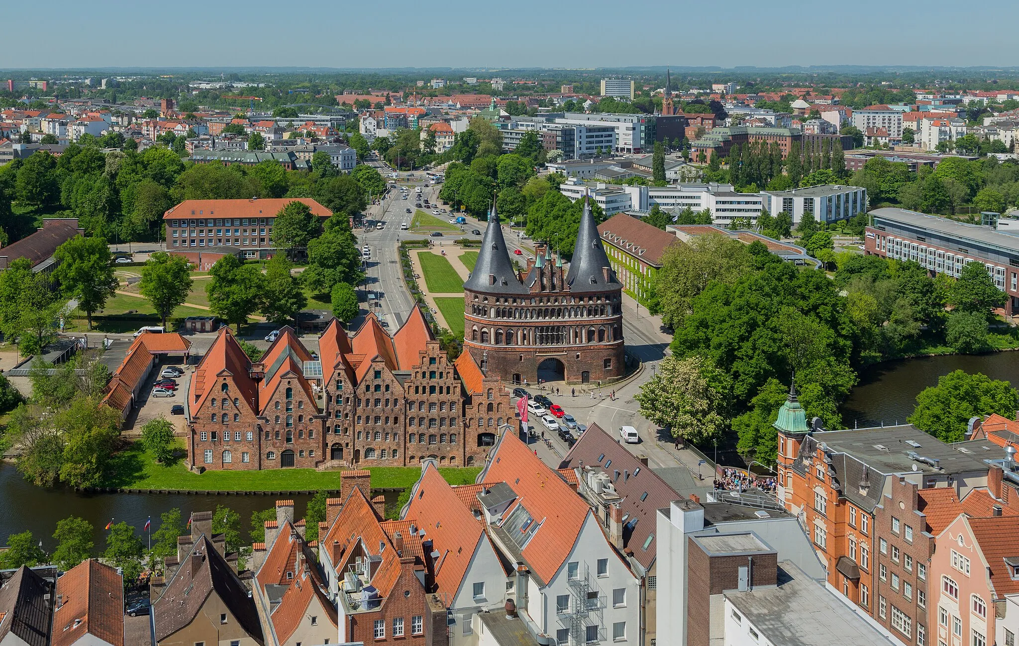 Photo showing: View from the tower of the St. Petri Church over Holsten Gate Square (Holstentorplatz) with the famous Holsten Gate (Holstentor) in the Hanseatic City of Lübeck (Lübeck-Altstadt), Lübeck, Schleswig-Holstein, Germany. The buildings on the left of the gate are the Lübeck Salt Storages (Lübecker Salzspeicher).