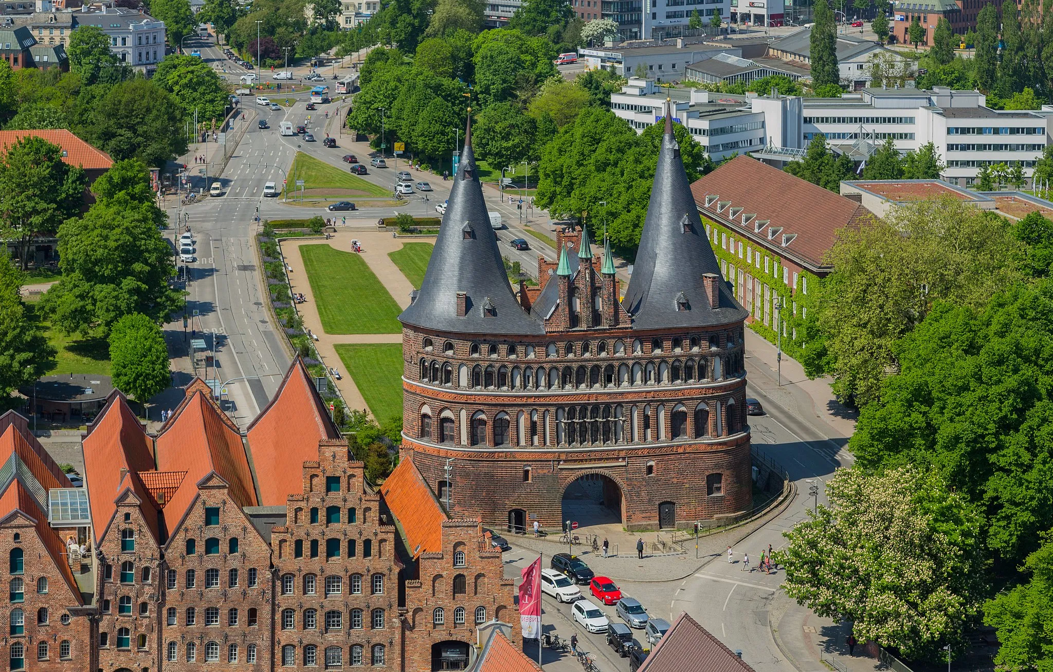 Photo showing: View from the tower of the St. Petri Church towards the famous Holsten Gate (Holstentor) on Holsten Gate Square (Holstentorplatz) in the Hanseatic City of Lübeck (Lübeck-Altstadt), Lübeck, Schleswig-Holstein, Germany. The buildings on the left of the gate are the Lübeck Salt Storages (Lübecker Salzspeicher).