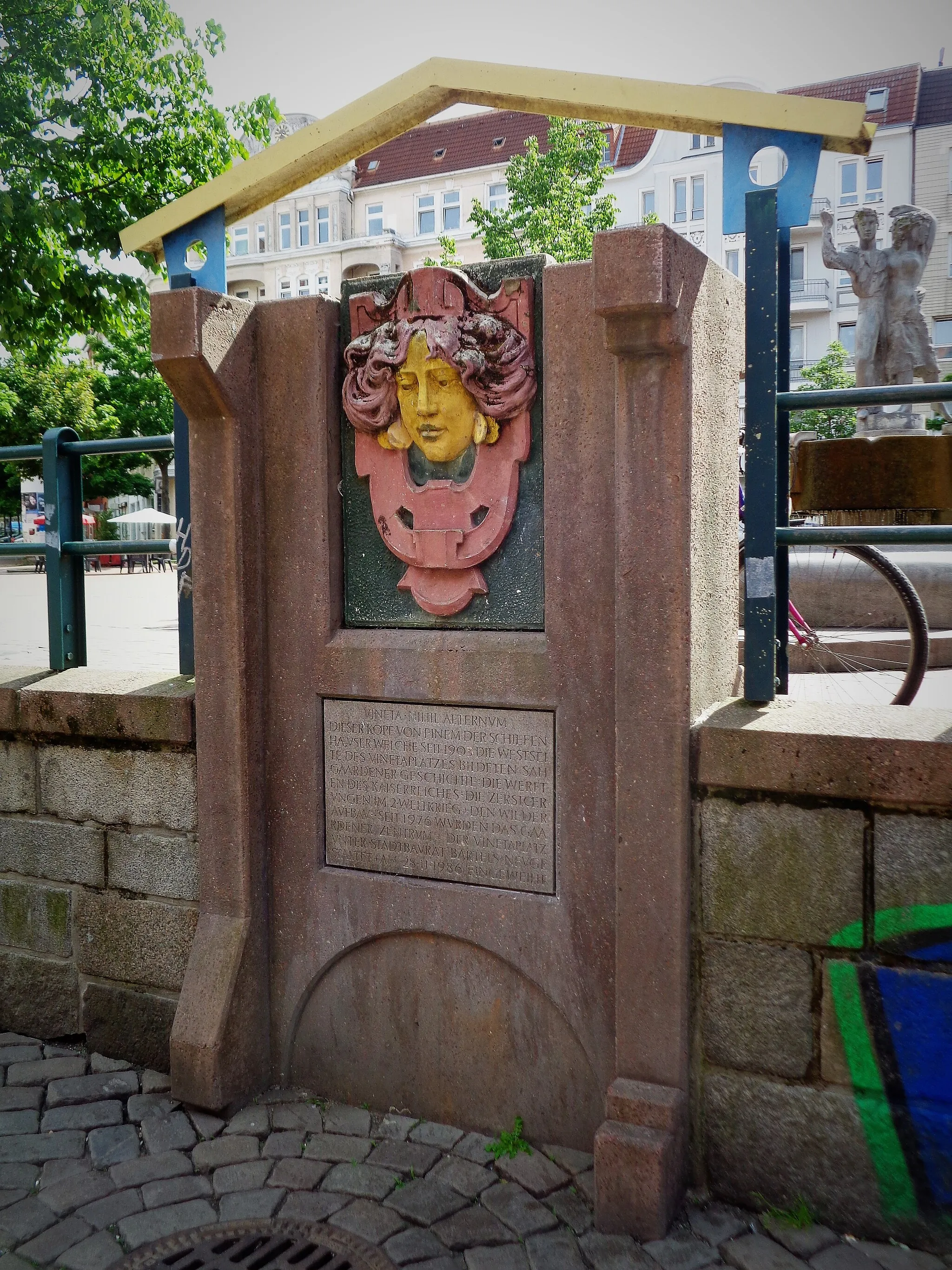 Photo showing: Dieser Kopf ist ein Überbleibsel von einem der „schiefen Häuser“, die seit 1905 die Westseite des Vinetaplatzes in Kiel-Gaarden-Ost bildeten. Er wurde nach 1976 in die Neugestaltung des Platzes einbezogen.