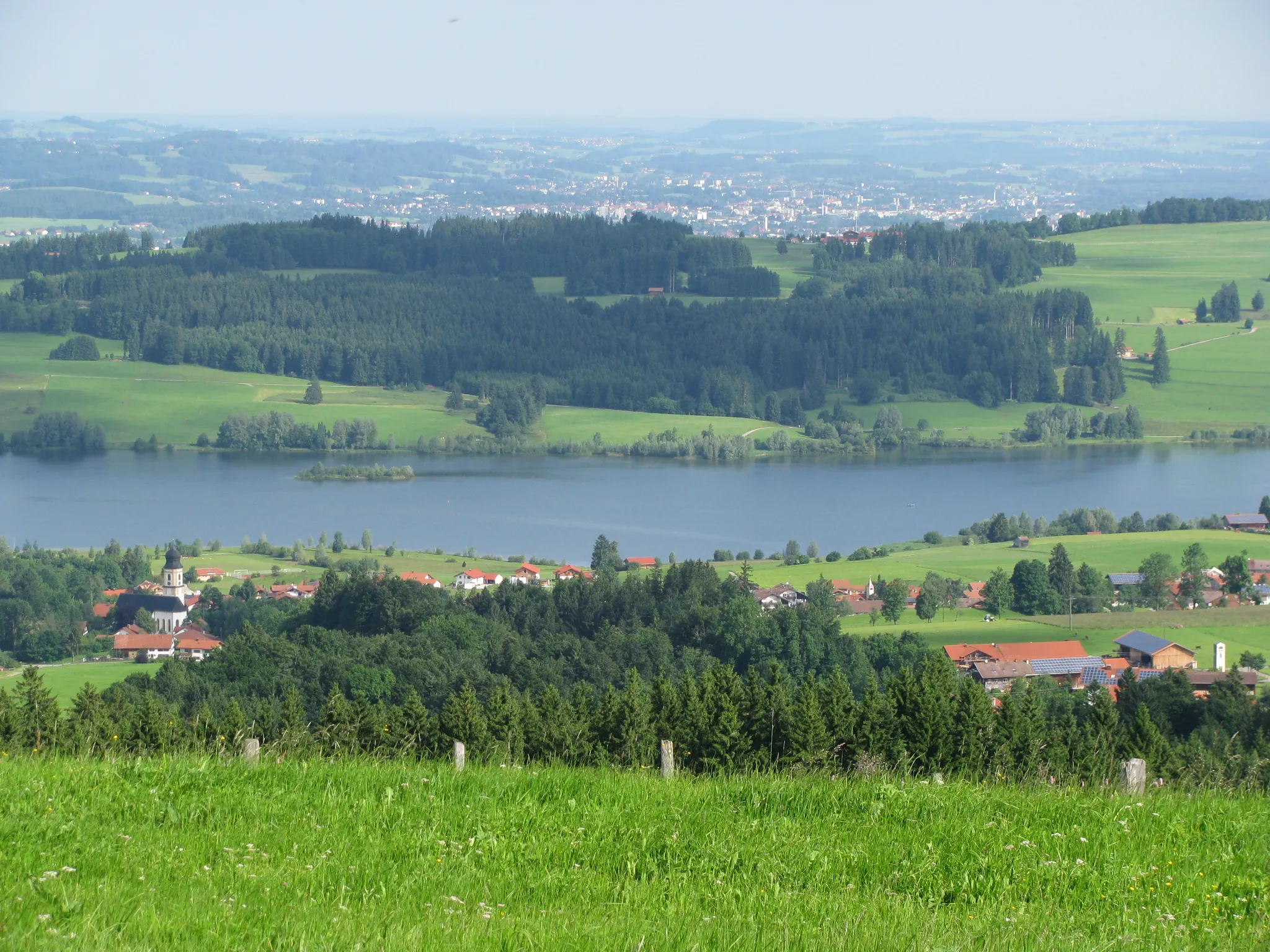 Photo showing: Petersthal (etwas durch Wald verdeckt) mit Pfarrkirche St. Peter und Paul, Rottachsee, im Hintergrund Kempten im Allgäu, von der Ellegg-Höhe aus gesehen