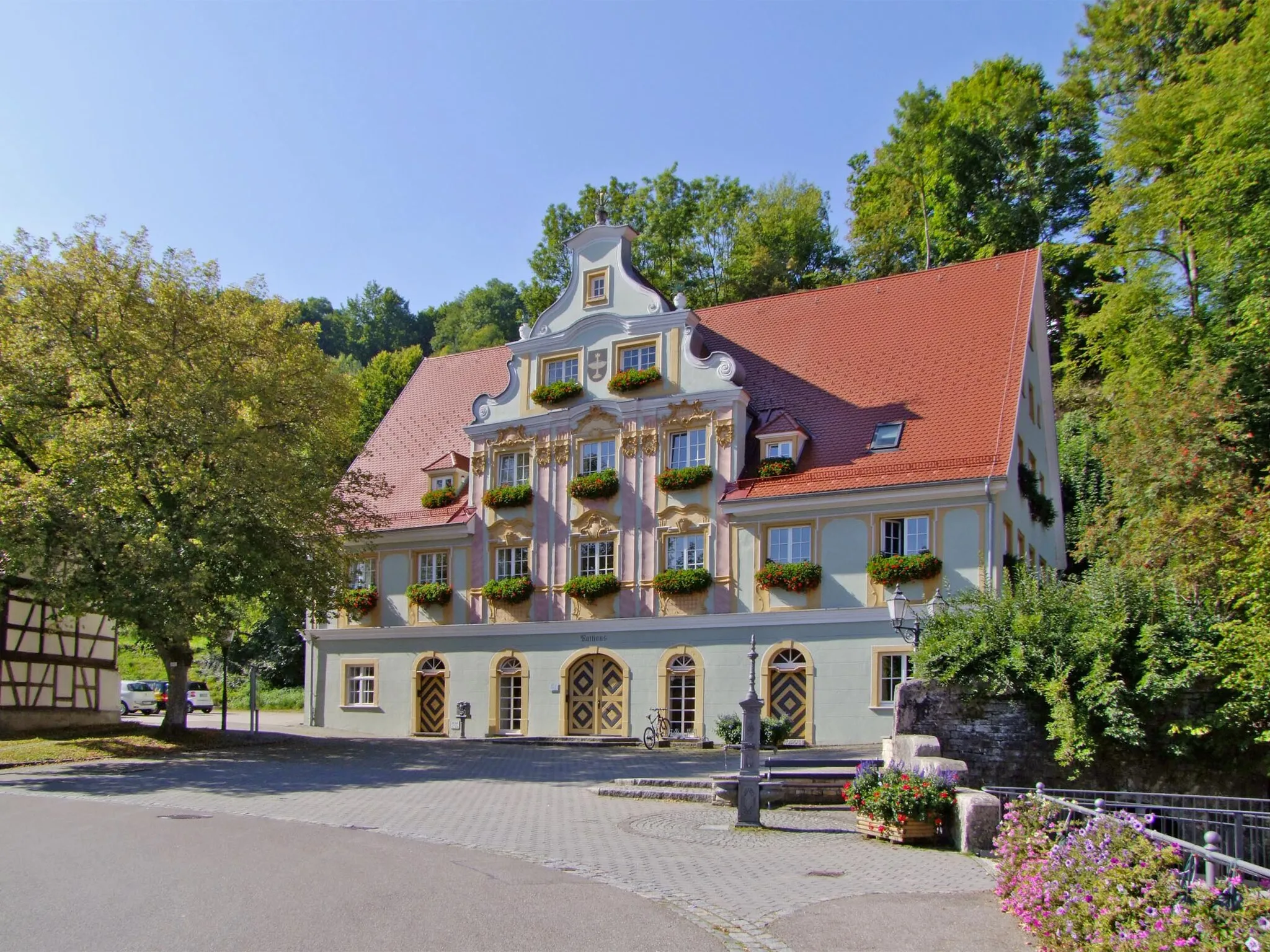 Photo showing: Das Gebäude entstand in seiner jetzigen Größe 1722 und war Wohnhaus, Brauerei und Wirtschaft „Zum Goldenen Löwen“. Der wohlhabende Besitzer Johann Georg Blezinger (1717-1795) ließ 1775 die Frontseite von einem unbekannten Künstler mit einem Rokoko-Schaugiebel versehen, so dass die Bevölkerung das Haus scherzhaft als „Blezinger-Palais“ bezeichnete. Blezinger war ein bedeutender Unternehmer besonders im Bereich der Verhüttungs- und Eisenindustrie Württembergs.
Seit 1885 ist das Gebäude das Rathaus der Gemeinde Königsbronn.