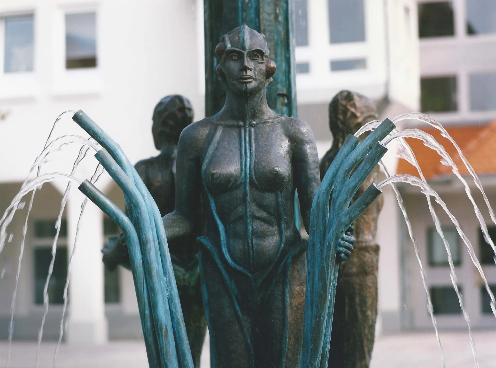 Photo showing: Jahreszeitenbrunnen (Röhrenfrau) von de:Ursula Stock, Bronze, Höhe 450 cm, 1991, Talheim, Rathausplatz 18.