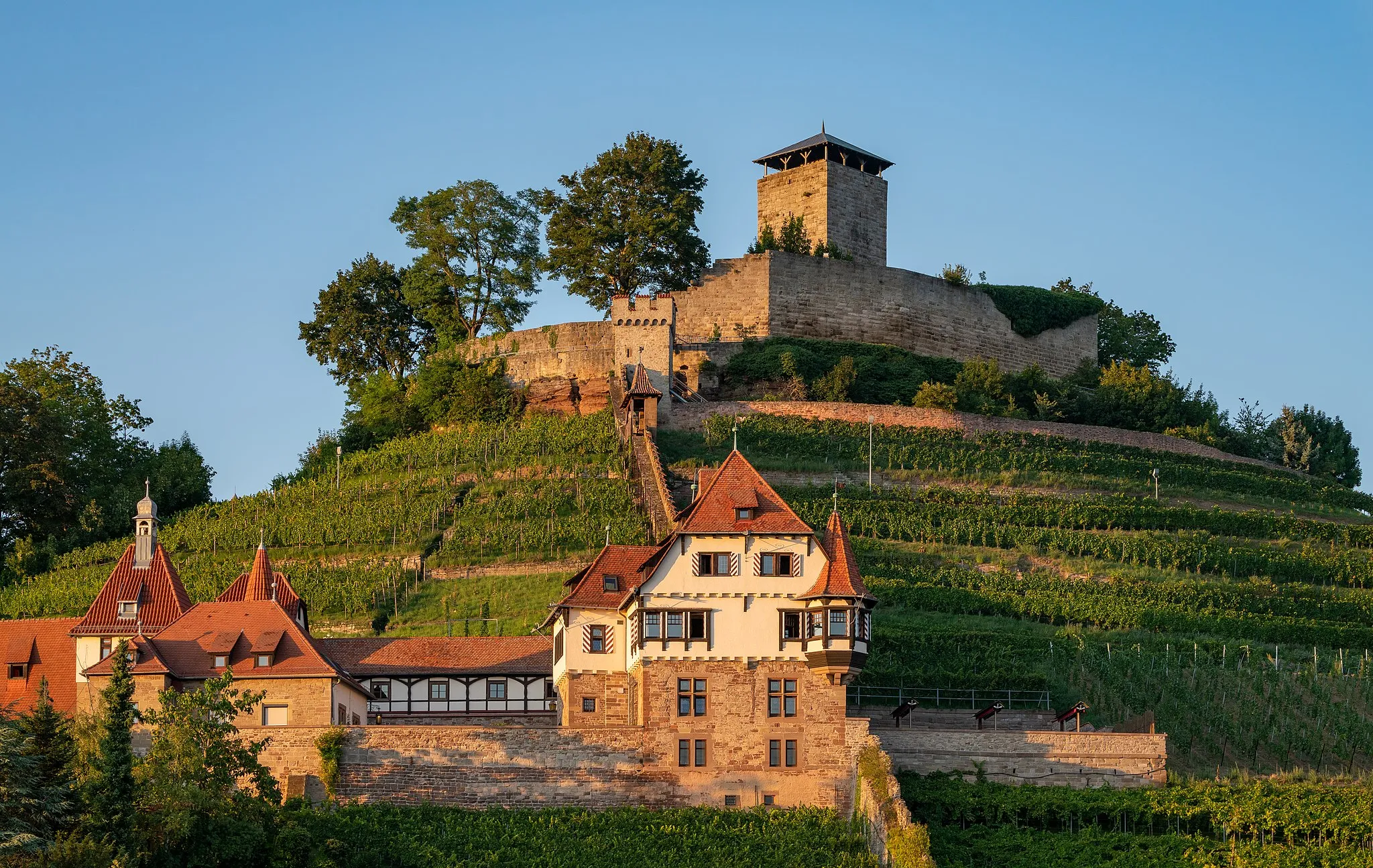 Photo showing: Beilstein, Württemberg, Germany: View from the Birkenweg to Hohenbeilstein Castle (on the top of the hill) and to the so-called Unteres Schloss, a listed villa built from 1906 to 1908 in historicist style. The photo has been taken in the evening sun, this explains the warm colours.