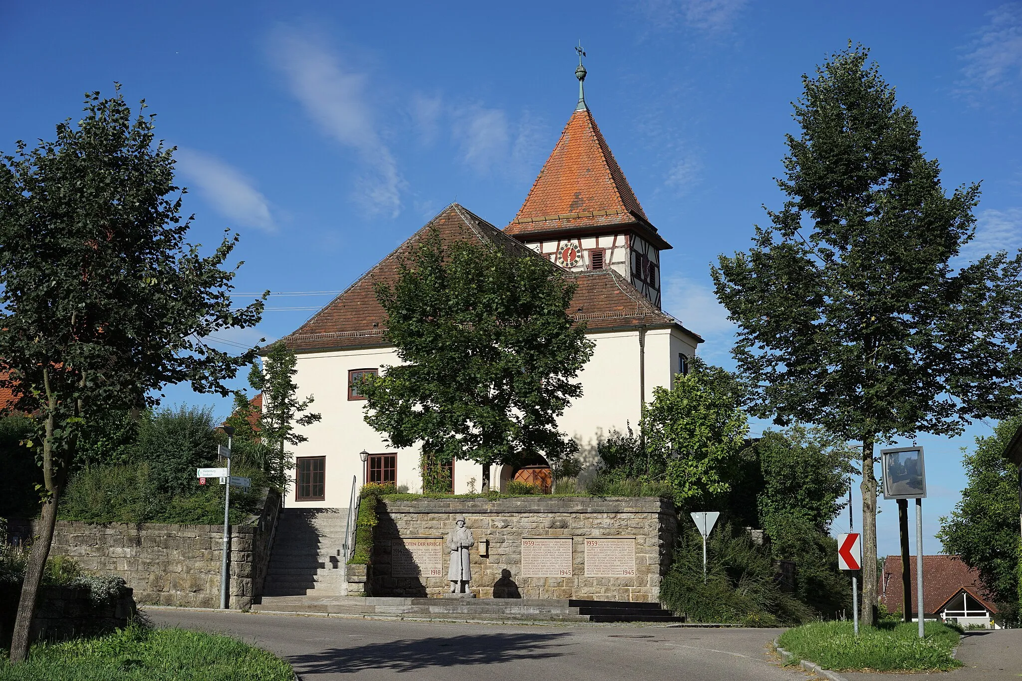 Photo showing: Schwäbisch Hall, Stadtteil Gailenkirchen: Blick von Westen auf die Pfarrkirche, davor das Gefallenendenkmal. Standort: auf der Waldenburger Straße.