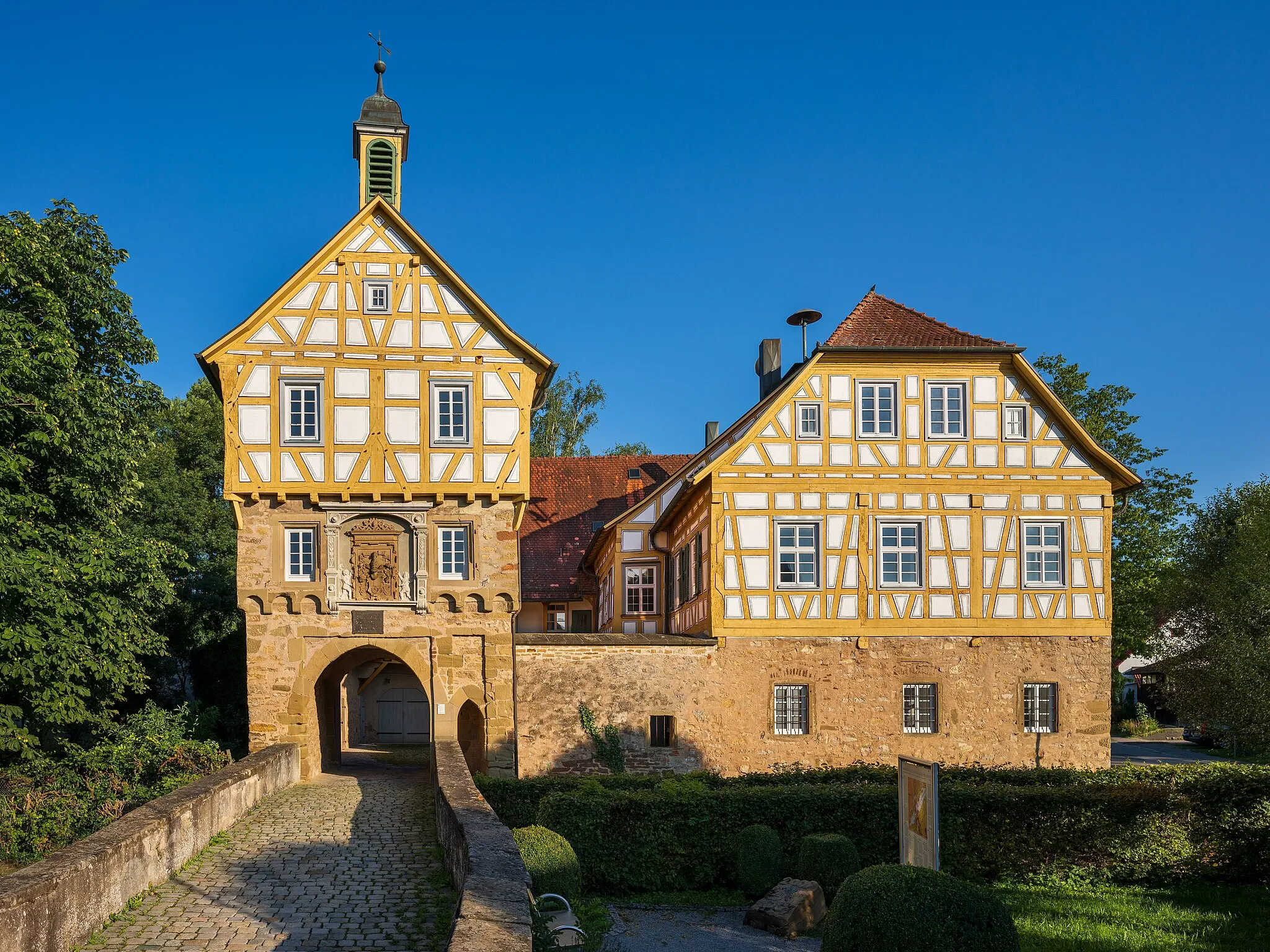 Photo showing: Steinheim an der Murr, Germany, district Höpfigheim: the so-called Schlössle (“little castle”), built in the middle ages as a moated castle and altered in the 16th century to a timber-framed manor house. View from 
the drive which has been built at the place of the former drawbridge. So you can imagine in the foreground the moat which has been filled. The vivid colours of the photo are due to the warm evening light.