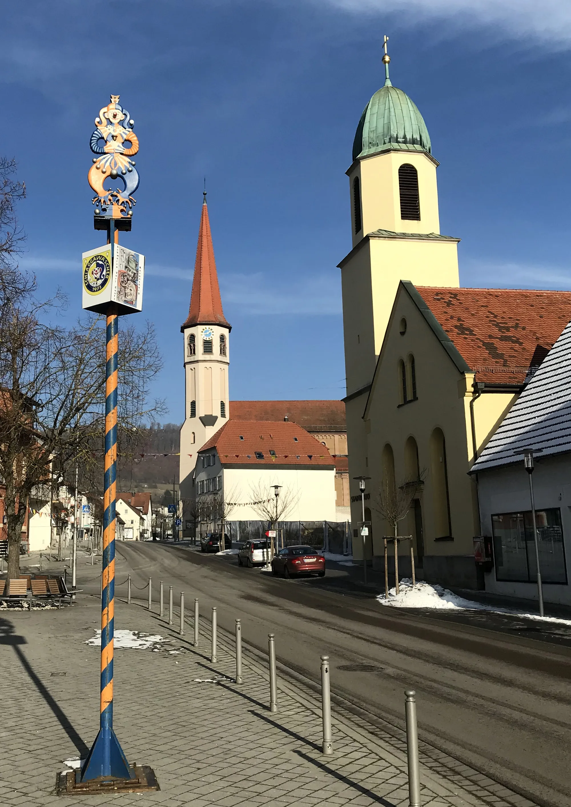 Photo showing: Oberkochen - Ortsmitte mit Narrenbaum der Narrenzunft Oberkochen „Schlagga-Wäscher“, katholischer Kirche (Mitte) und ehemaliger evangelischer Kirche (heute Stadtbibliothek, rechts)