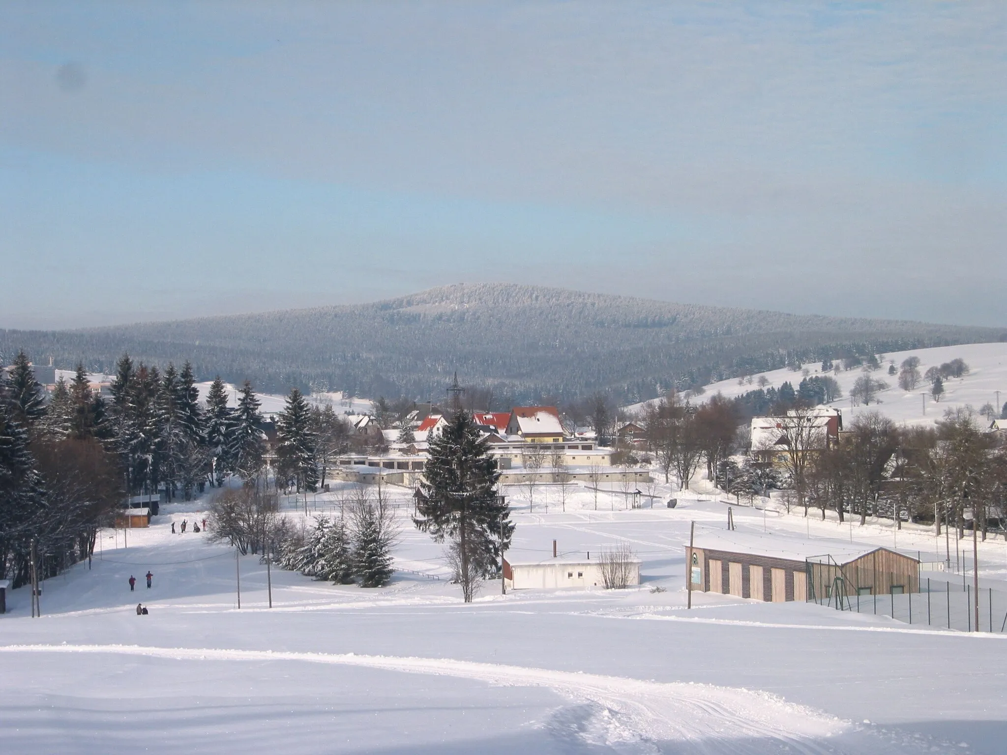 Photo showing: Großer Finsterberg, 944 m ü. NN., Thüringer Wald, Blick vom Hückel bei Schmiedefeld am Rennsteig, im Vordergrund ein Teil der Ortschaft Schmiedefeld am Rennsteig mit dem auf ca. 710 m ü. NN gelegenen Sportplatz der zugleich Zieleinlauf des Guths-Muths-Rennsteiglauf ist