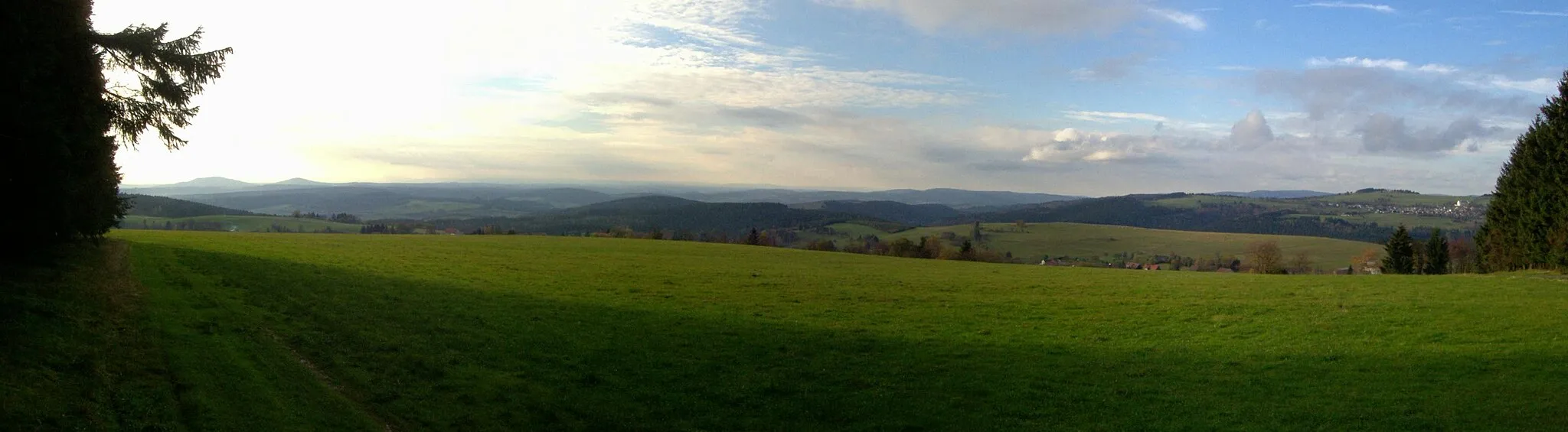 Photo showing: Blick vom Eckartsberg (760 m) bei Waffenrod-Hinterrod im Thüringer Schiefergebirge Links der Große (679 m) und der Kleine (641 m) Gleichberg im Grabfeld hinter dem Klingeberg (677 m); rechts der Mitte der Priemäusel (625 m) vor dem Solaberg (577 m, links davon) im Buntsandstein-Vorland; rechts der Bildmitte im Hintergrund das Gewerbegebiet Suhl-Friedberg und der Kleine Thüringer Wald mit Schneeberg (692m) und Schleusinger Berg (671m). Nach rechts folgt der Kohlberg (718 m), der weiter rechts in den Simmersberg (781 m) mit dem Ort Schnett übergeht; dazwischen im Hintergrund der Adlersberg (849 m) mit dem Neuhäuser Hügel (891 m) im höheren Thüringer Wald, rechts ist im Vordergrund der Ort Waffenrod-Hinterrod erkennbar, der durch das tiefe Bibertal vom Simmersberg getrennt ist.