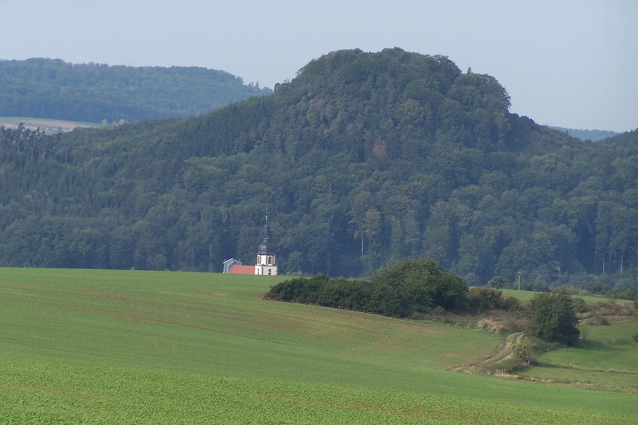 Photo showing: Blick von Osten auf den Bocksberg und die Kirche von Schleid im Ulstertal.