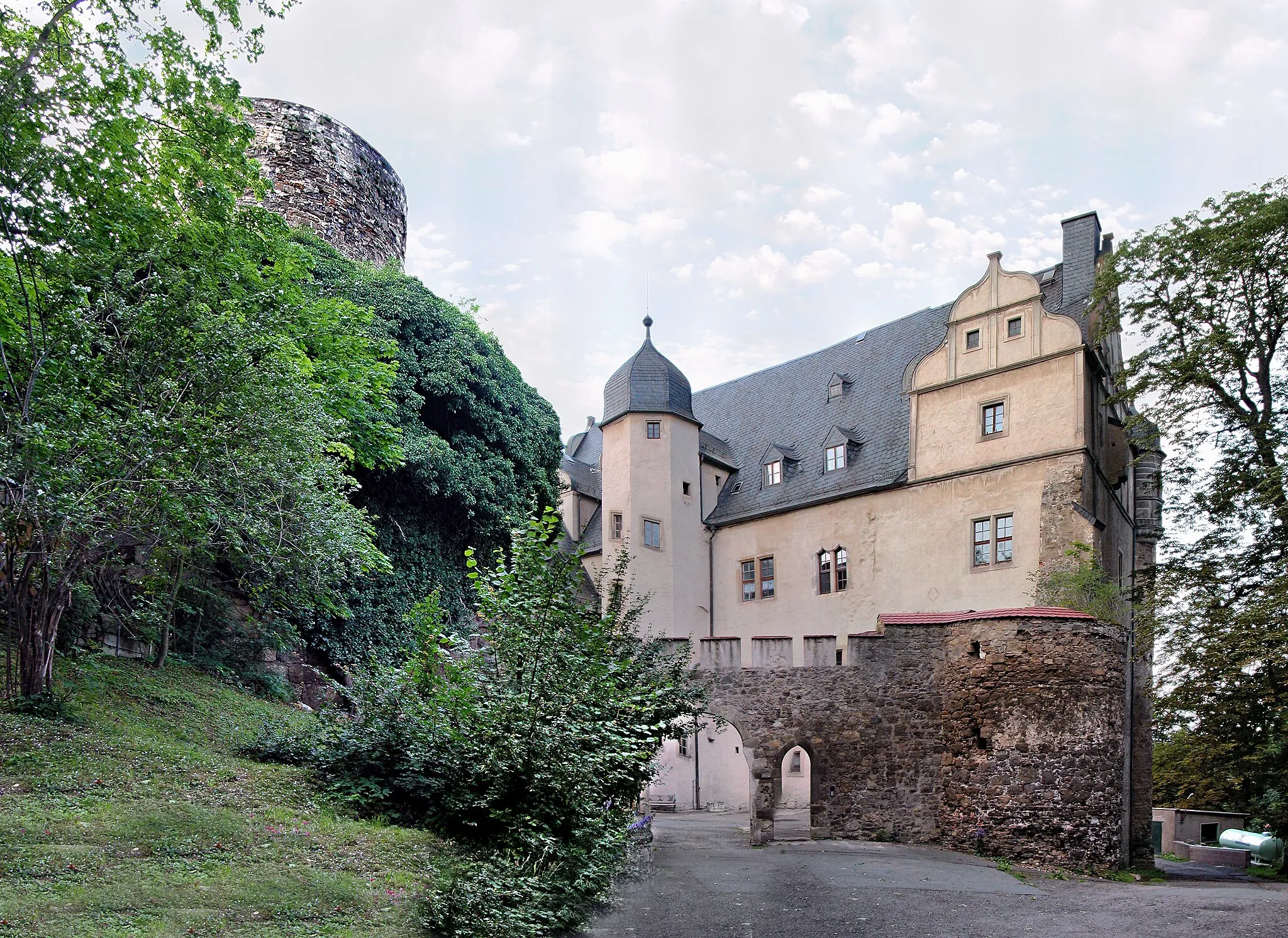 Photo showing: 04.07.2012    07333  Könitz (Unterwellenborn), Schloßberg 16: Schloß (GMP: 50.651241,11.489464). Um 800 begann der Bau der Burganlage durch einen Ritter von Conz. Von seinem Namen leitet sich auch der Name des Adelsgeschlechts Könitz ab. Die  Burg ist eine 1438 urkundlich genannte, unregelmäßige Anlage. 1562 wird der Bau des Schlosses in seiner noch heute zu sehenden Form vollendet. Im Westen und Süden je ein Flügel, im Osten mächtiger Bergfried, im Hof Treppenturm mit reichem spätgotischem Balkon, im Westflügel Remter mit Balkendecke. 1608 fällt das Schloss an die Grafen von Schwarzburg-Rudolstadt. In der DDR-Zeit dient das Schloß seit 1955 als Unterkunft für geistig behinderte Menschen / Feierabendheim. Es wird heute [... 2012] von der Arbeiterwohlfahrt Saalfeld-Rudolstadt geführt. Sicht von der Zufahrt.                [DSCNn4209-4211.TIF]20120704015MDR.JPG(c)Blobelt