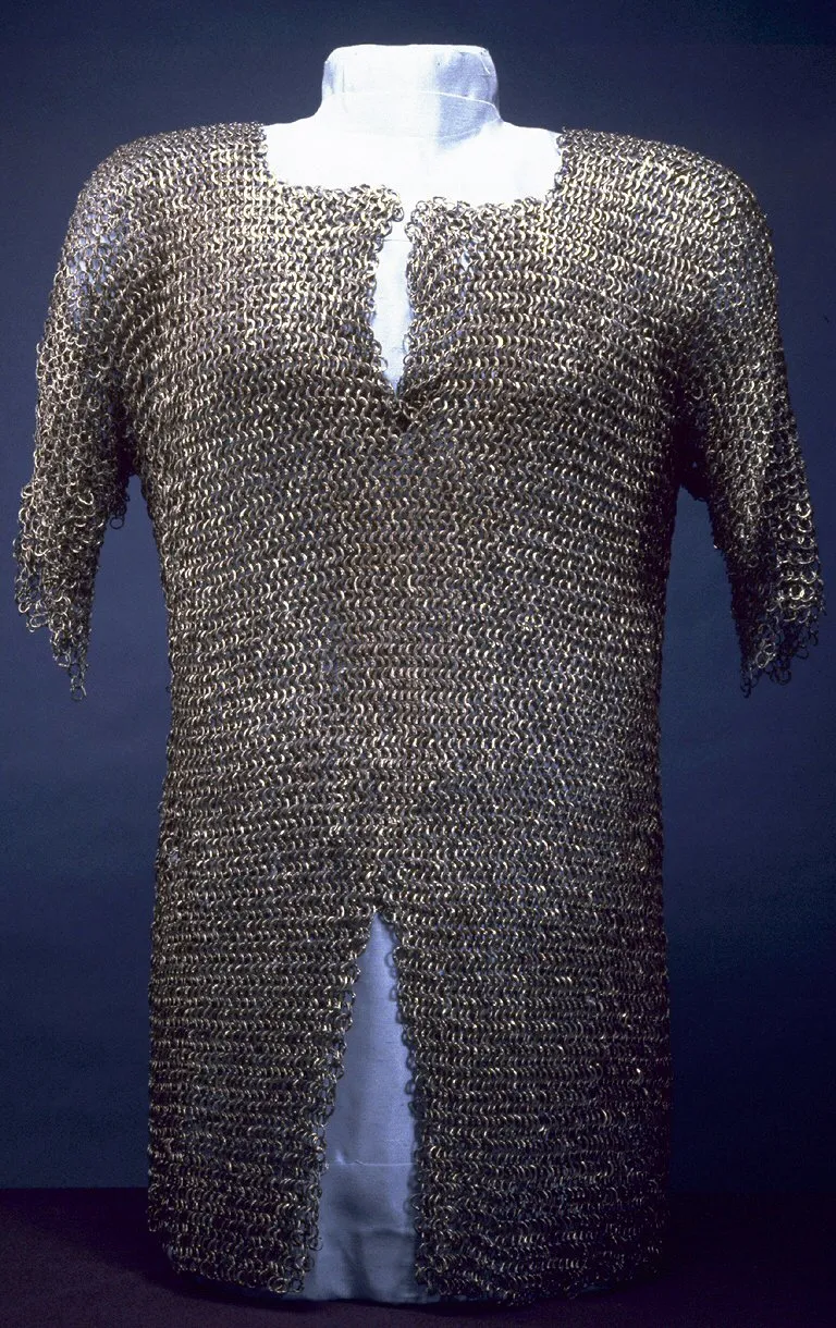Photo showing: The mail (from the Latin word for mesh) worn by the Romans was made from interlocking iron rings, but the development during the Middle Ages of the capacity to refine iron into steel-harder and more durable than iron-meant higher quality armor as well as weapons. A typical shirt has about 30,000 rings, each individually riveted, and might weigh about 16 or 17 pounds. A shirt of mail was worn over a padded garment to protect the skin and soften the effect of a blow. It is more flexible than plate armor but is heavier for the wearer because all the weight is suspended from the shoulders. Mail was gradually replaced by plate armor in the 14th century, though it continued to be worn by some infantry soldiers and to fill gaps in a knight's armor.