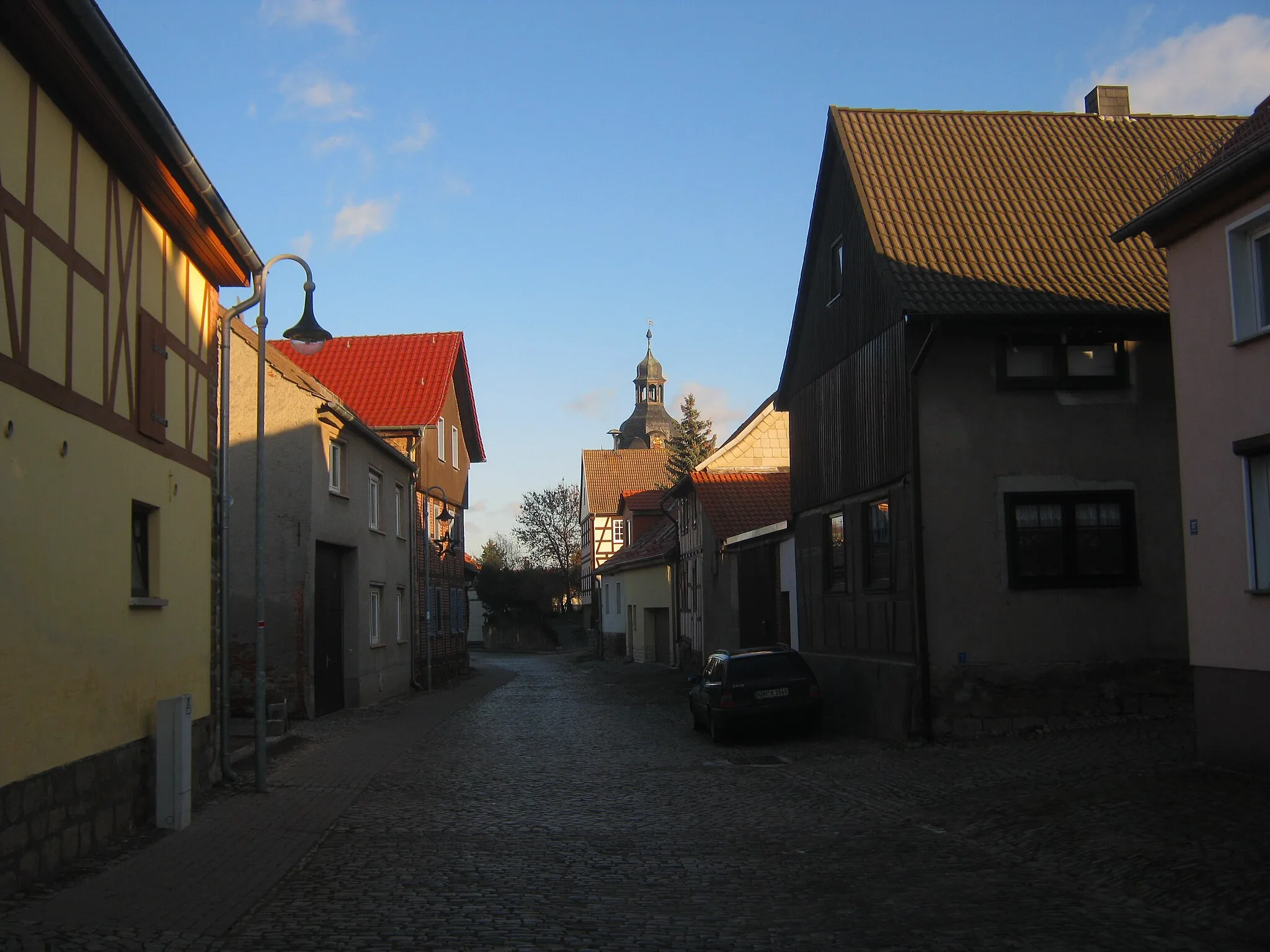 Photo showing: Auf der Hauptstrasse von Hamma. Im Hintergrund der Kirchturm von Sankt Trinitatis.