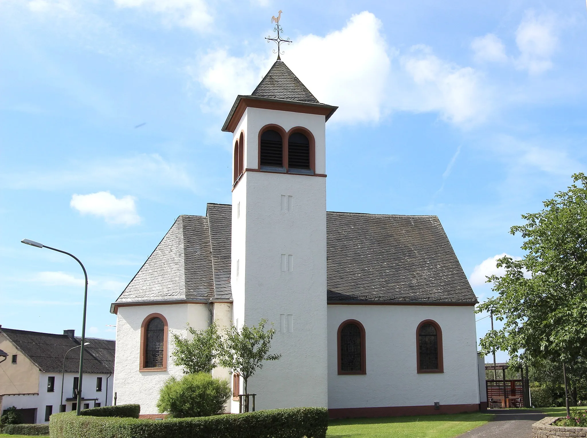 Photo showing: 54597 Reuth, Dorfstraße. Die einschiffige Kapelle von 1950 mit einem an der Nordseite angebauten Glockenturm von 1972. An der Ostwand des Chorraumes befindet sich, durch den Altar verdeckt, ein noch erhalten gebliebenes gotisches Sakramentshäuschen. Aufnahme von 2017.