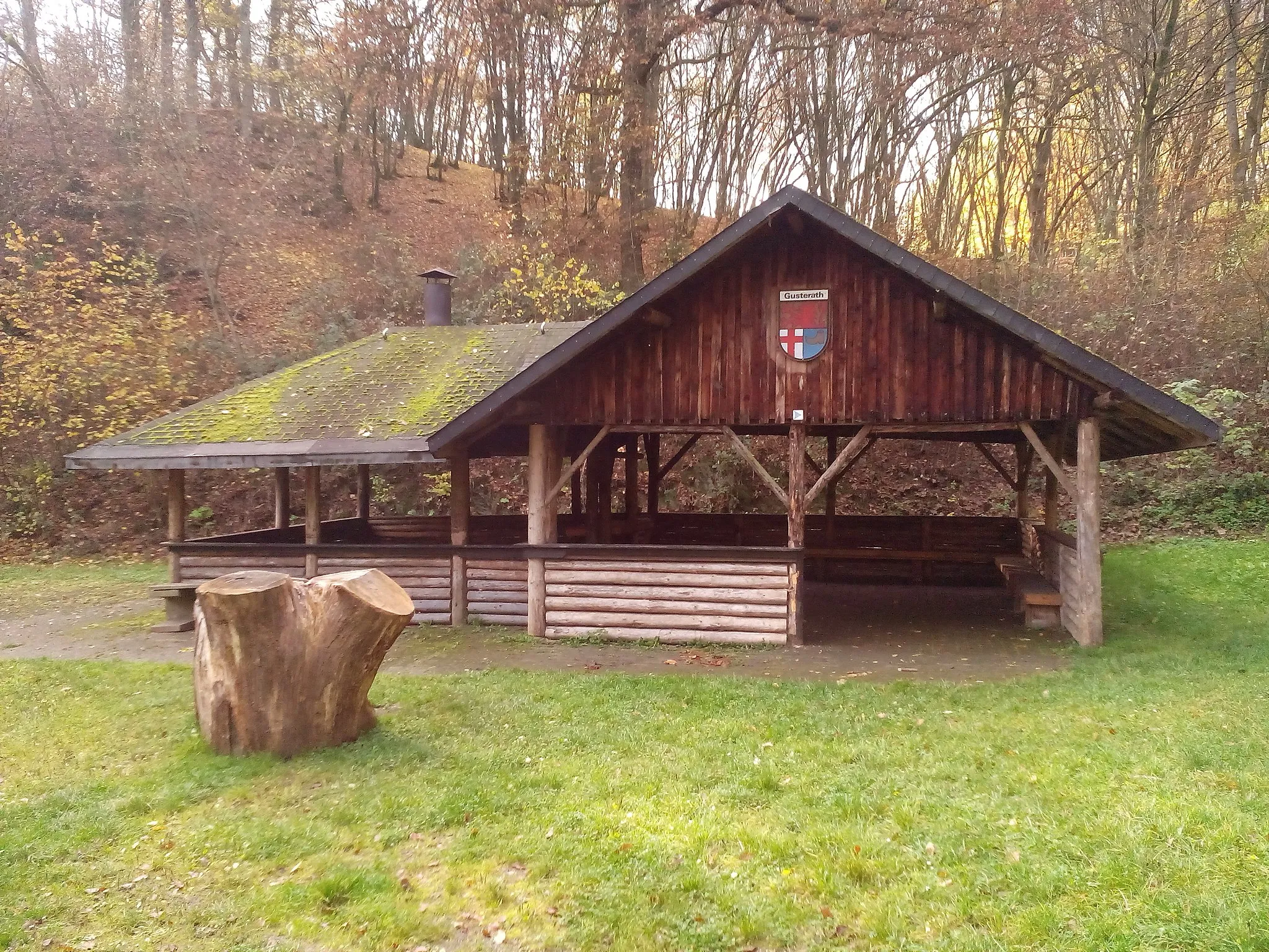 Photo showing: Die Gusterather Grillhütte im Herbst 2015, im Vordergrund steht der Baumstamm eines ehemaligen Naturdenkmals