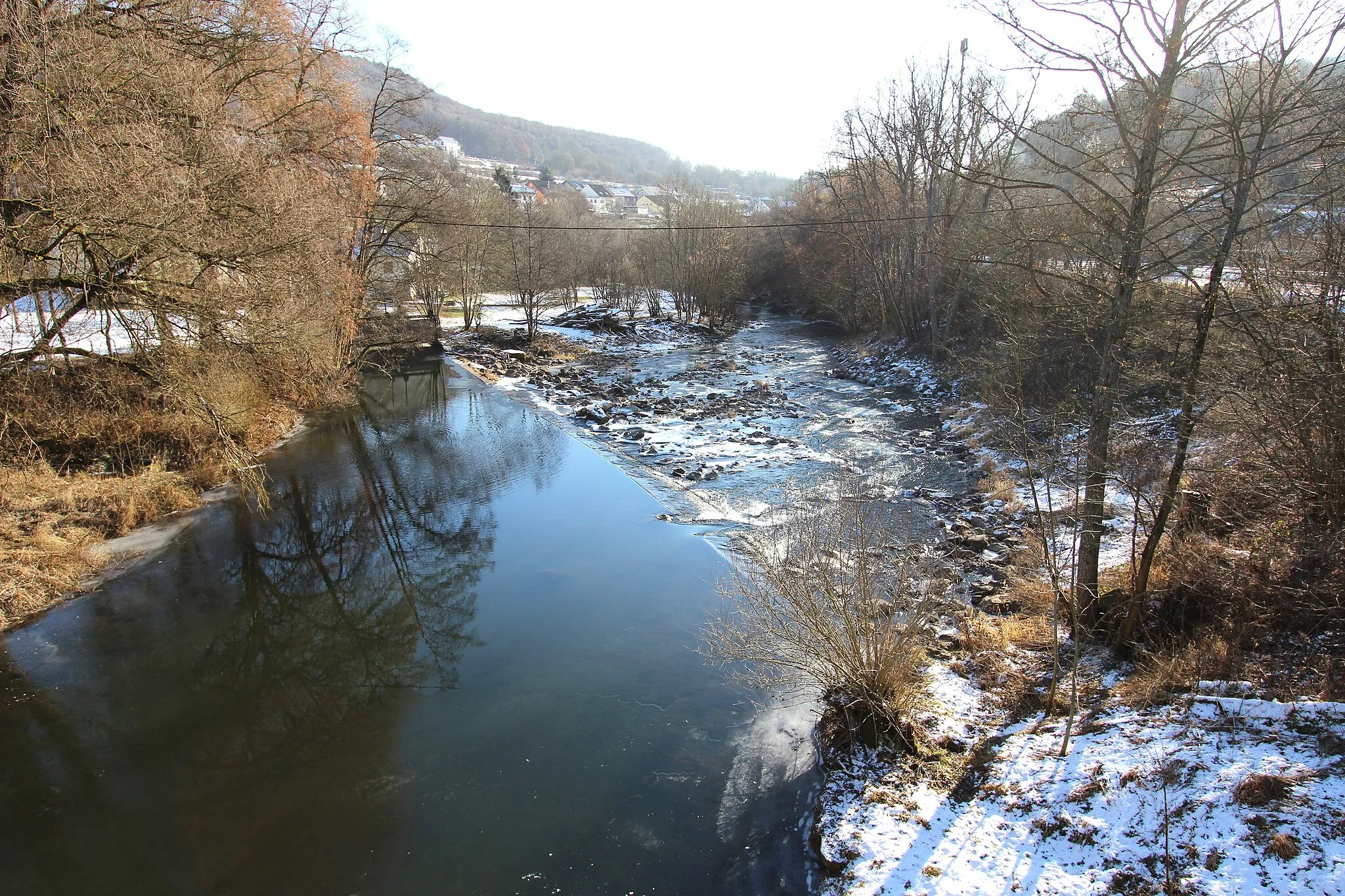 Photo showing: 54636 Hüttingen an der Kyll. Die Kyll durch Hüttingen. Aufnahme aus 2017 von der K33 Brücke am Ortseingang.