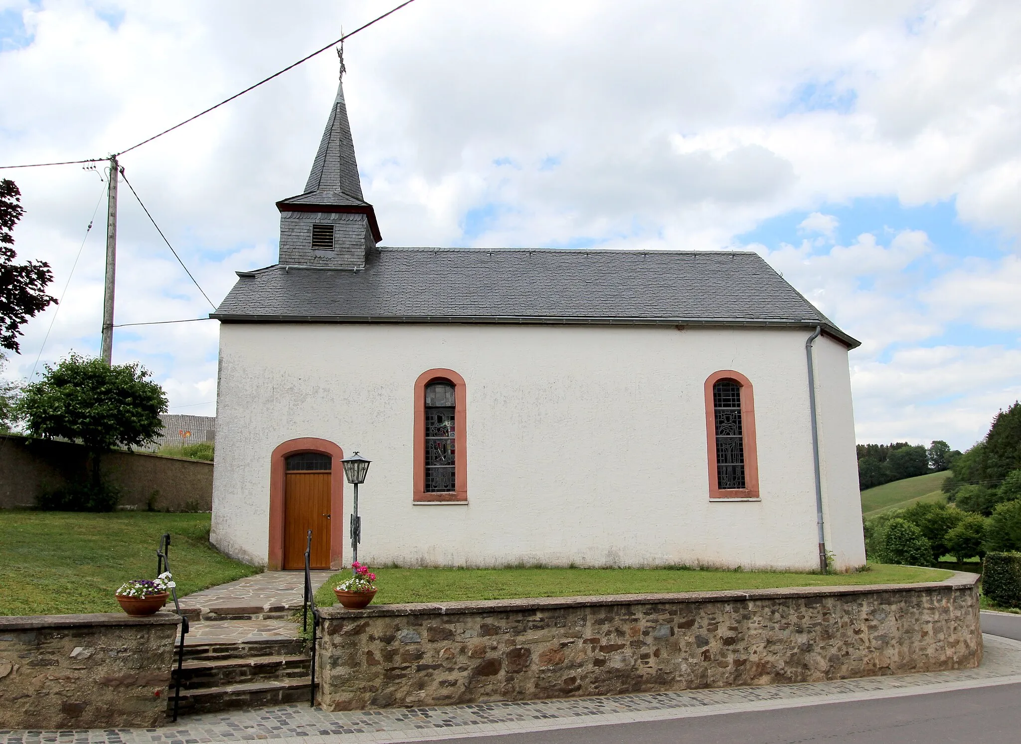 Photo showing: 54597 Auw bei Prüm, Ortsteil Schlausenbach, Hauptstraße, Görresweg. Schmaler Saalbau mit Spitzhelmdachreiter, angeblich von 1658, bezeichnet 1691; mit Ausstattung. Aufnahme von 2017.