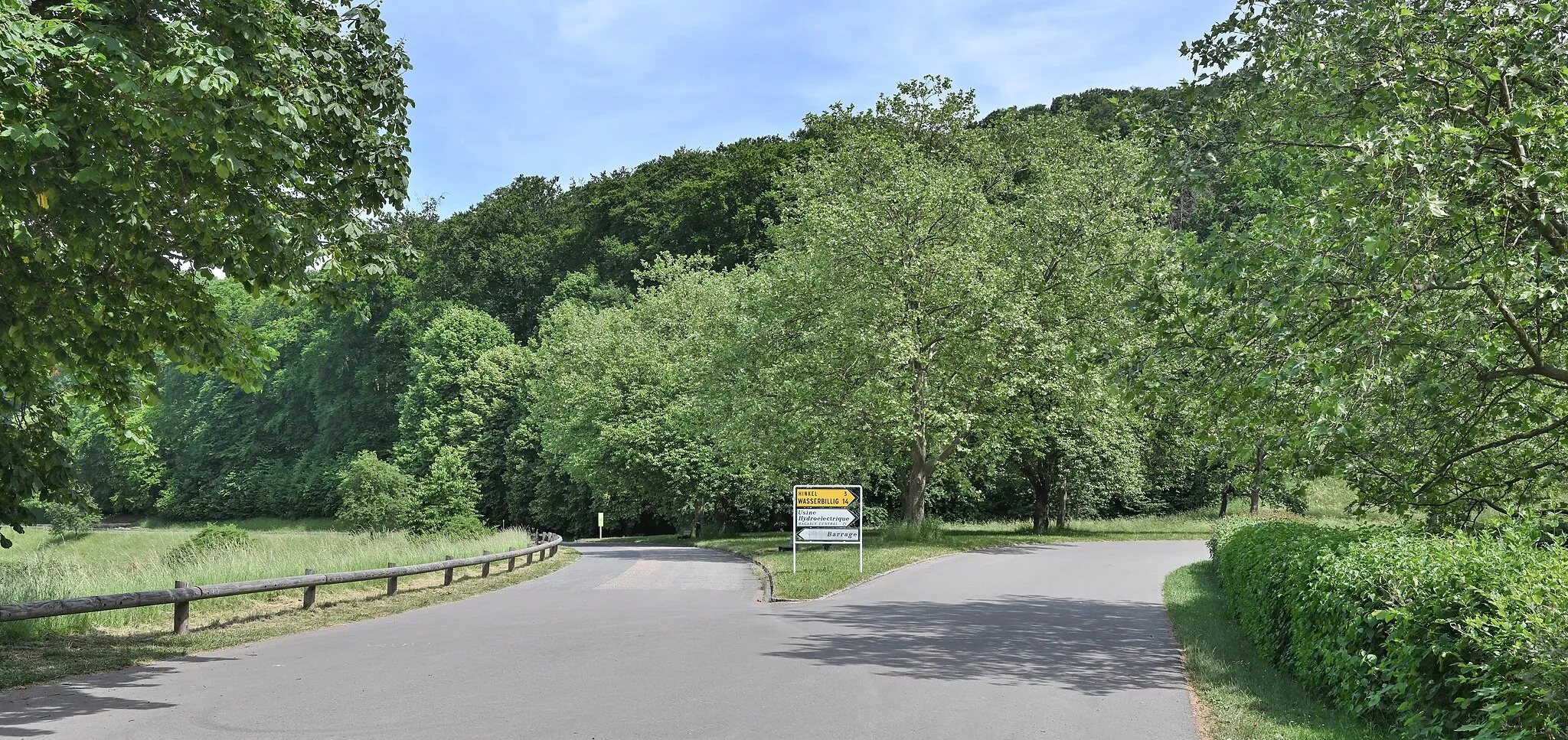 Photo showing: Intersection at Rosport in Luxembourg. The green sign in the left background is for the nature reserve Rosport-Hëlt.