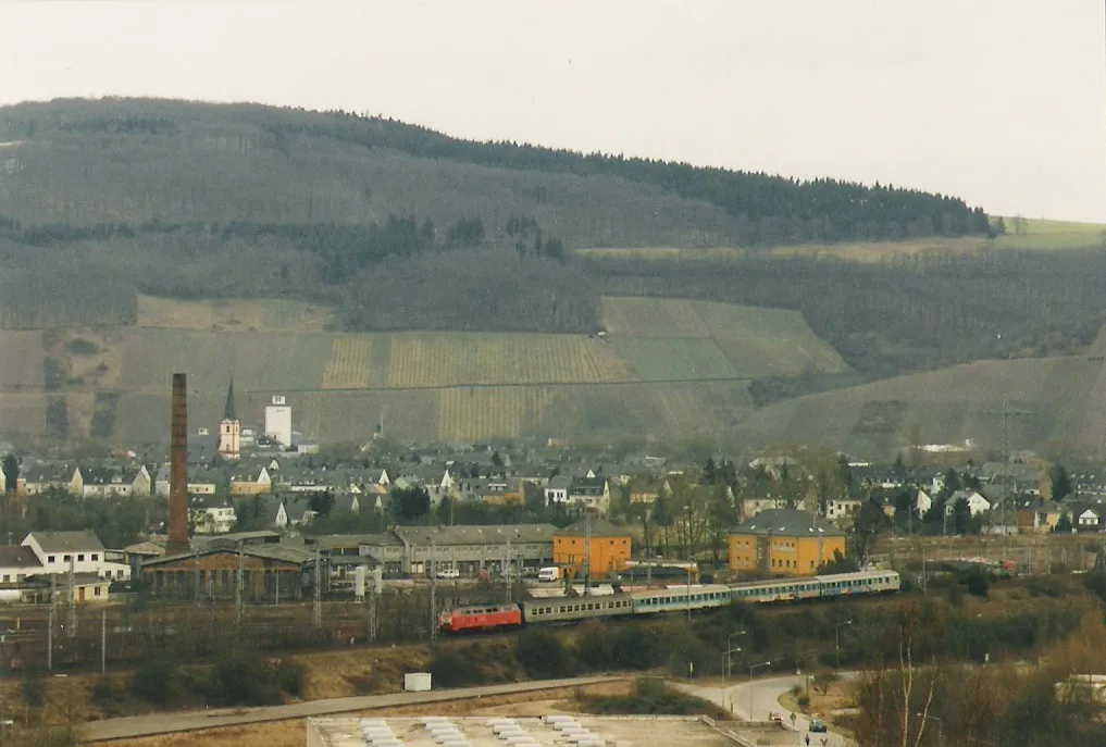 Photo showing: Aufnahme des ehemaligen Bahnbetriebwerkes Ehrang in Trier 1996. Im Vordergrund fährt ein Regionalexpress Trier-Köln, der mit einer Lokomotive der Baureihe 215 bespannt ist.