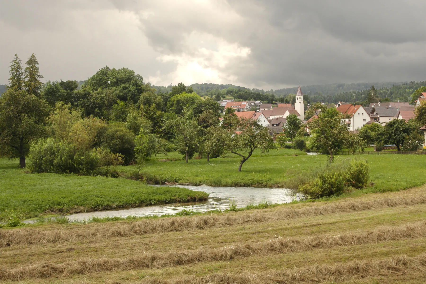 Photo showing: Small community “Oberschmeien” (part of Sigmaringen), off main routes in a narrow, picturesque valley (other photo: Typical karst valley) , Western Swabian Alb. Although the Swabian Alb is karstic, there is a perennial rivulet in the valley. The valley has a prominent hydrogeological history going far back into tertiary times. Erosion, deeper than 100 m,  happened mainly in periglacial times.
An old single railway, although being the highly frequented railway line Tübingen-Balingen-Sigmaringen follows smoothly the valley’s geomorphology. Prosperity today is a problem as the valley has no space for modern, technology-oriented agriculture.