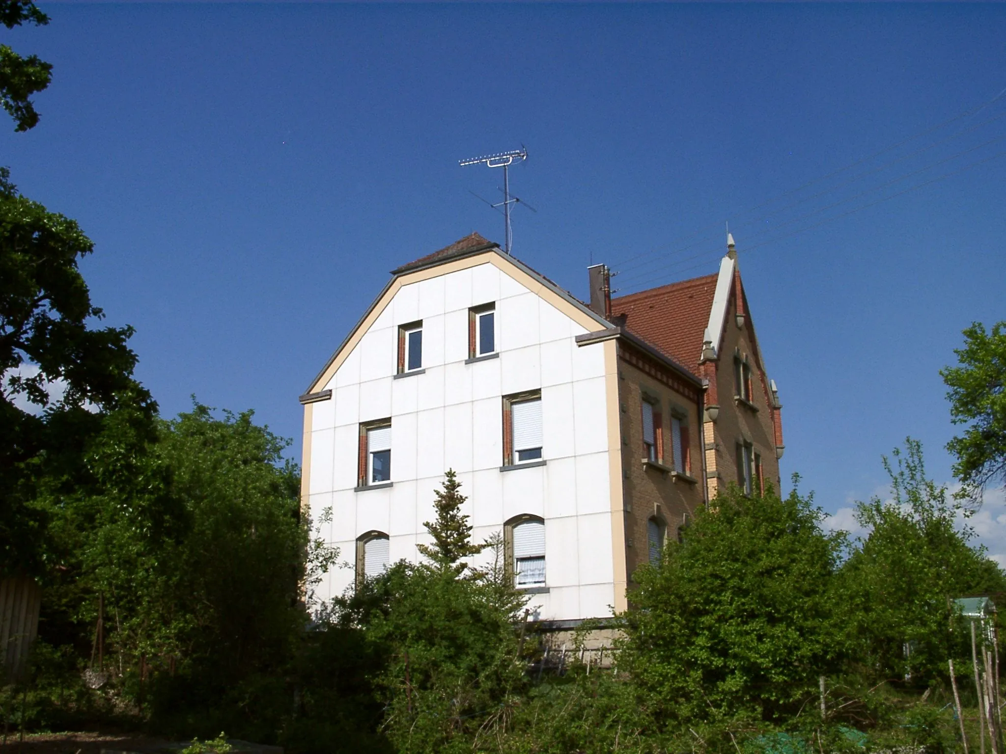 Photo showing: Western side of the parsonage of Schwalldorf, a suburban district of Rottenburg am Neckar in the German state of Baden-Württemberg. The brick building was built at the beginning of the 20th century (1905?). The west facade of the building was renovated a few years ago.