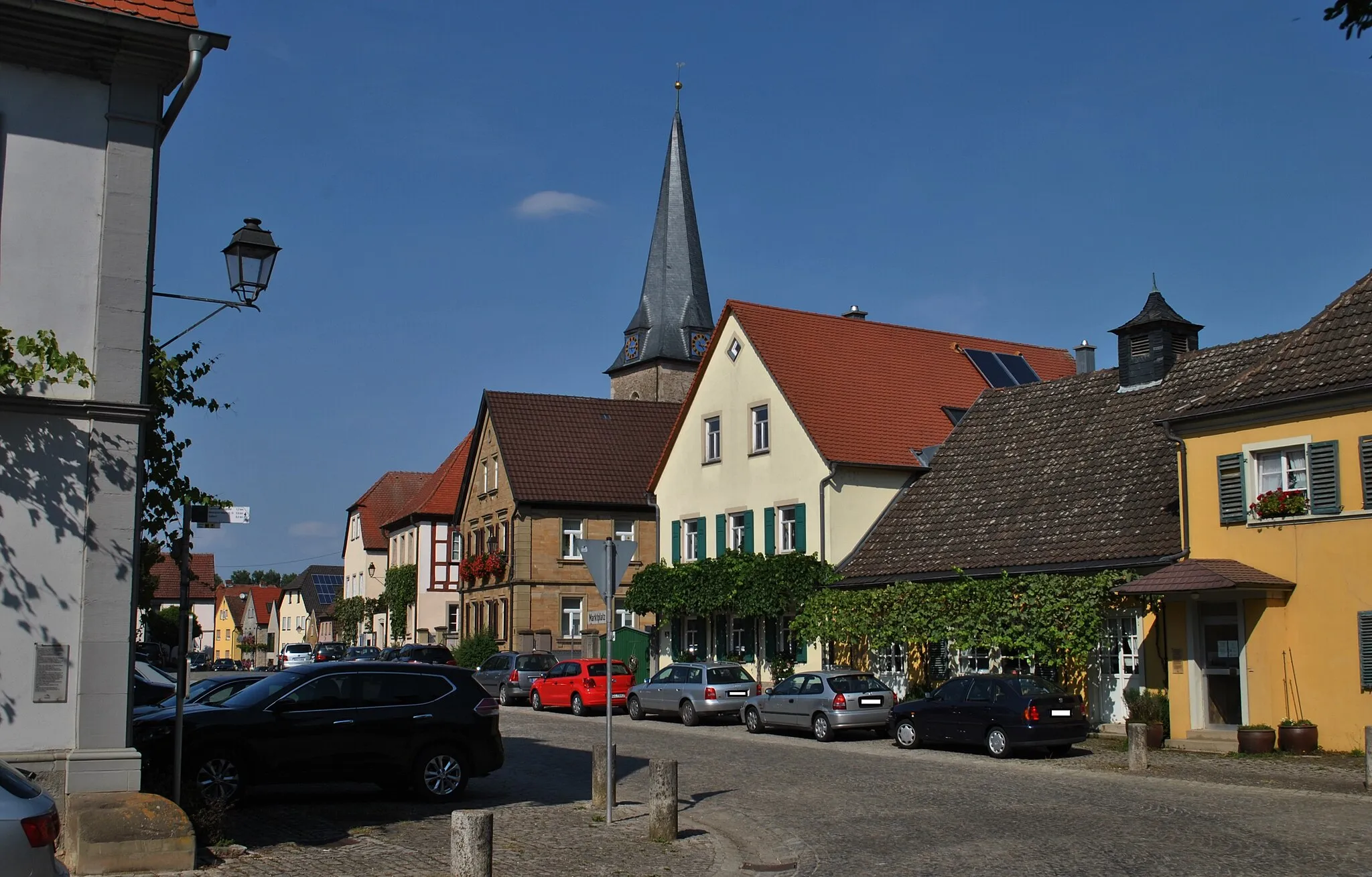 Photo showing: Der langgestreckte Marktplatz ist zugleich Dorf- und Schlossvorplatz. Er ist auf die Mittelachse des Schlosses ausgerichtet und wird an den Langseiten von Bauernhäusern des 19. Jahrhunderts in Giebelstellung begleitet. Nach Norden schließt ihn das ehemalige Rathaus ab. Der an der Nordostseite des Platzes liegende Kirchenbezirk ist in das Ensemble einbezogen.