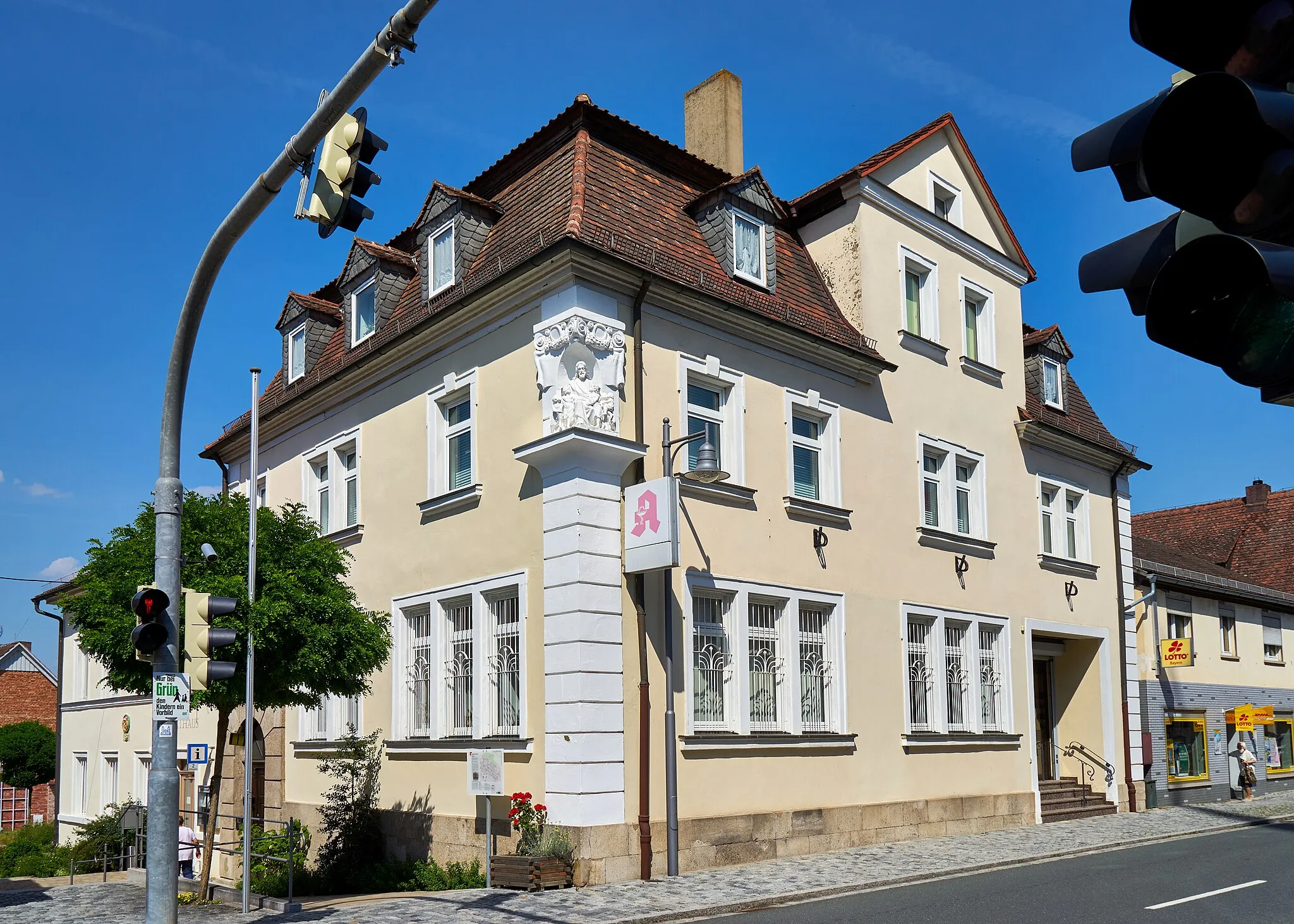 Photo showing: Wohn- und Geschäftshaus, Apotheke, zweigeschossiger barockisierender Eckbau mit Mansarddach, Sockel und Portalrahmung aus Haustein, genutete Ecklisenen und geohrte Fensterrahmungen, Zwerchhaus und Giebelgauben, mit Christusfigur, bezeichnet 1907