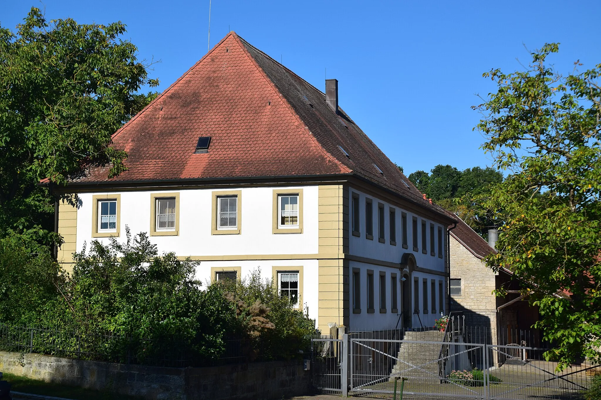 Photo showing: zweigeschossiger, massiver Walmdachbau mit zweiläufiger Außentreppe, Hausteingliederung mit genuteten Ecklisenen, Fensterrahmungen und stichbogiger Türrahmung, Gurt- und Dachgesims