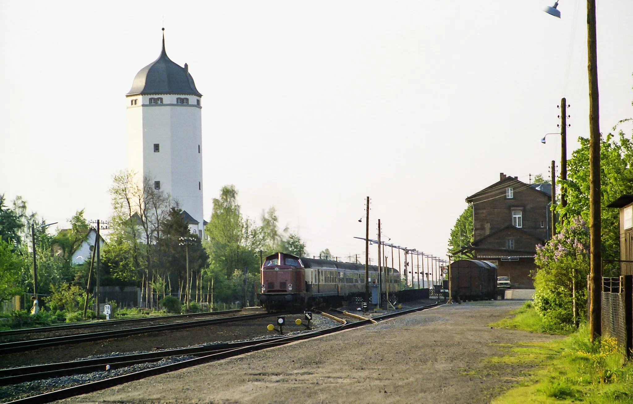 Photo showing: Locomotive 212 358-6 (Hanau depot) in front of train E 2357 (Frankfurt / M Hbf - Stuttgart Hbf) at the departure in Seligenstadt (Hesse) on May 14, 1980, in the background the historic water tower