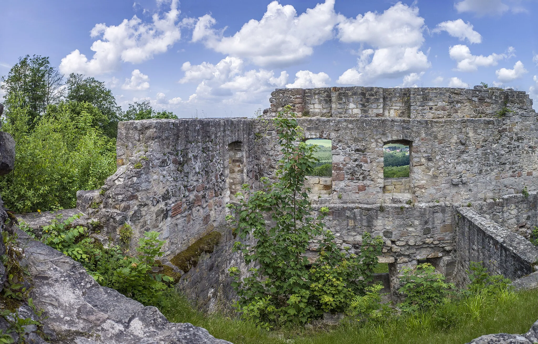 Photo showing: Burgruine Bramberg, Mauerzüge in Bruchsteinmauerwerk mit Werksteinen, im Südwesten Außentor 15./16. Jh., nach Nordwesten jüngerer Gebäudetrakt des 16. Jh., im Südosten Kernburg des 14. Jh. mit Zugang durch Torturm des 16. Jh., Randhausburg mit Ring- und Halsgraben des 12. Jh., nach Zerstörung 1186 Neubau der Kernburg um 1330/40 durch das Hochstift Würzburg, im 16. Jh. grundlegende Umgestaltung, nach 1560 aufgegeben