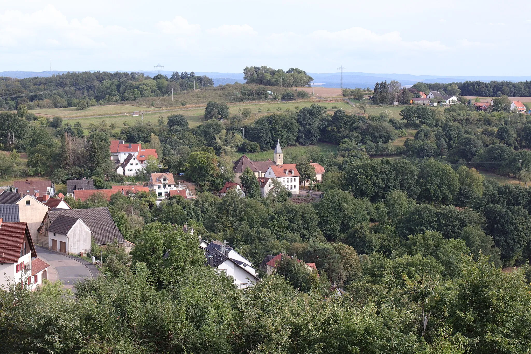 Photo showing: Johannesberg (Bavaria), district Rueckersbach, view to the part of the village descending to the catholic church (Hoersteiner Strasse 14) and adjacent buildings