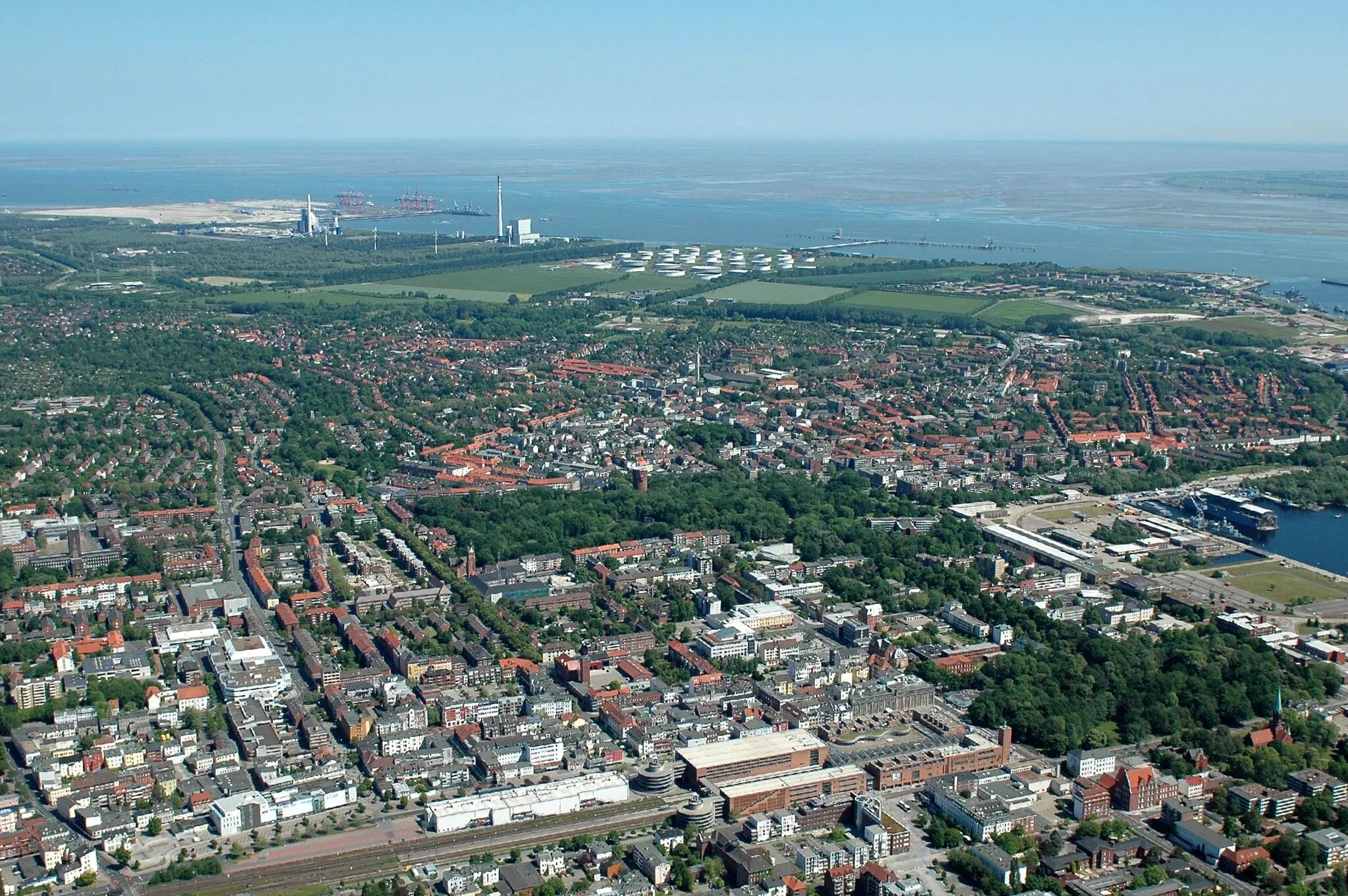 Photo showing: Wilhelmshaven Stadtzentrum, Blick nach Norden, unten der Bahnhof, rechts der Arsenalhafen, oben das Industriegebiet mit Raffinerie, Kraftwerken und JadeWeserPort
(Fotoflug vom Flugplatz Nordholz-Spieka über Cuxhaven und Wilhelmshaven)