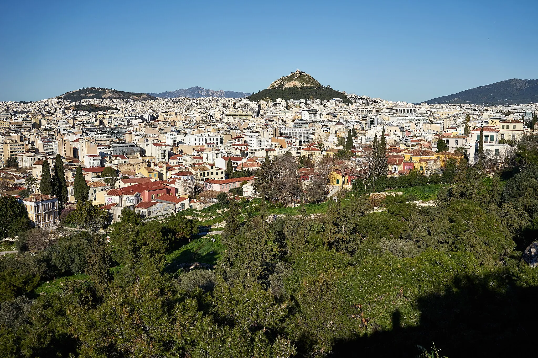 Photo showing: The archaeological site of the Areopagus from the Areopagus Hill on March 31, 2020. In the distance, Mount Lycabettus and the Hill of Tourkovounia.