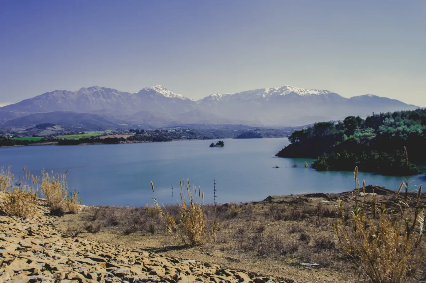 Photo showing: Asteri Dam or Parapiros Dam. View of the dam lake. The temporary islet with Saint Theodores' chapel of Mitopolis village sinking. Mount Erymanthos in background (Achaea).