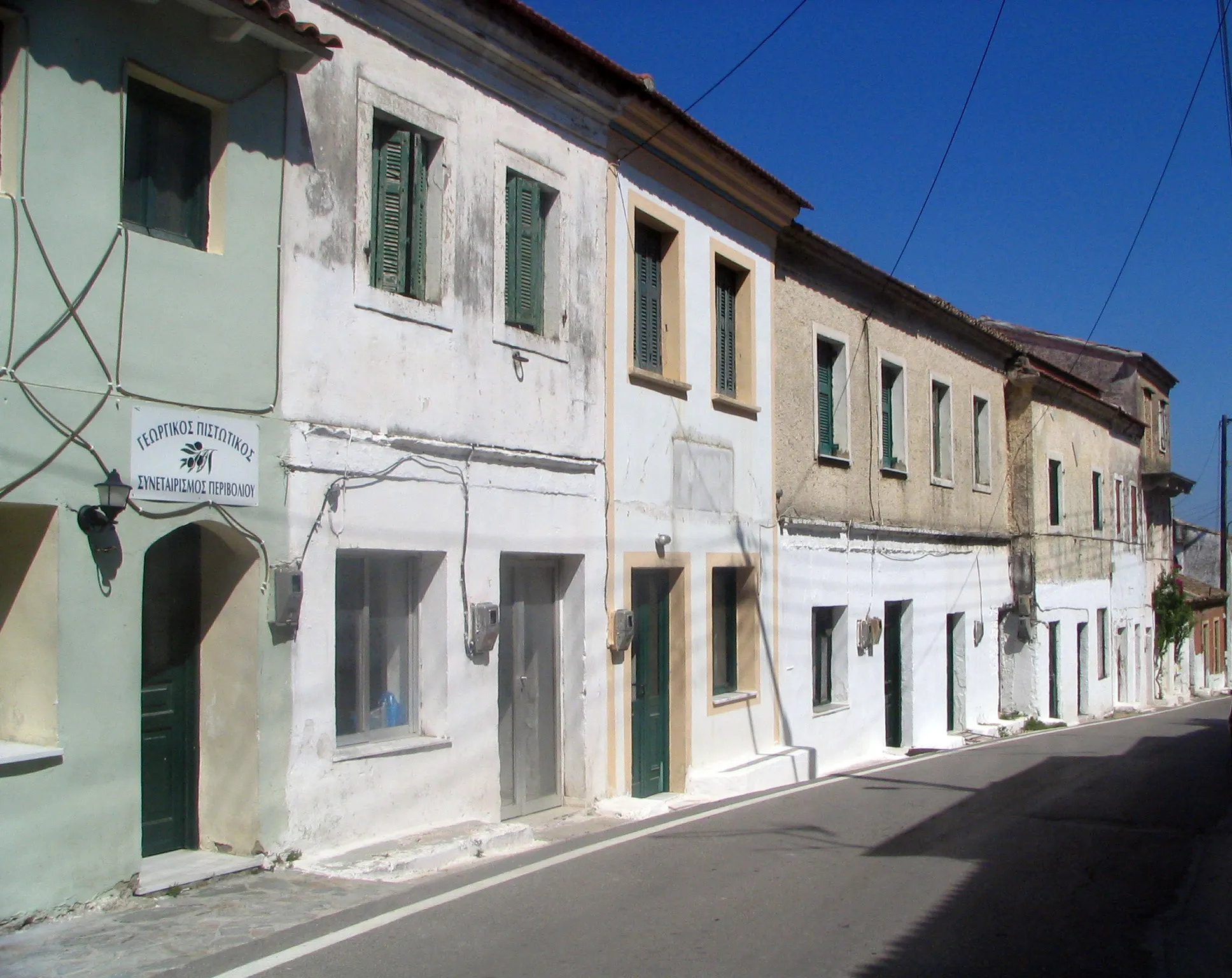 Photo showing: A street in a village in Corfu, Greece
The inscription in Greek reads "ΓΕΩΡΓΙΚΟΣ  ΠΙΣΤΩΤΙΚΟΣ  ΣΥΝΕΤΑΙΡΙΣΜΟΣ  ΠΕΡΙΒΟΛΙΟΎ"
Agricultural Credit Cooperative of Perivoli

So, the village is probably Perivoli (the alternative would be nearby Vitalades)