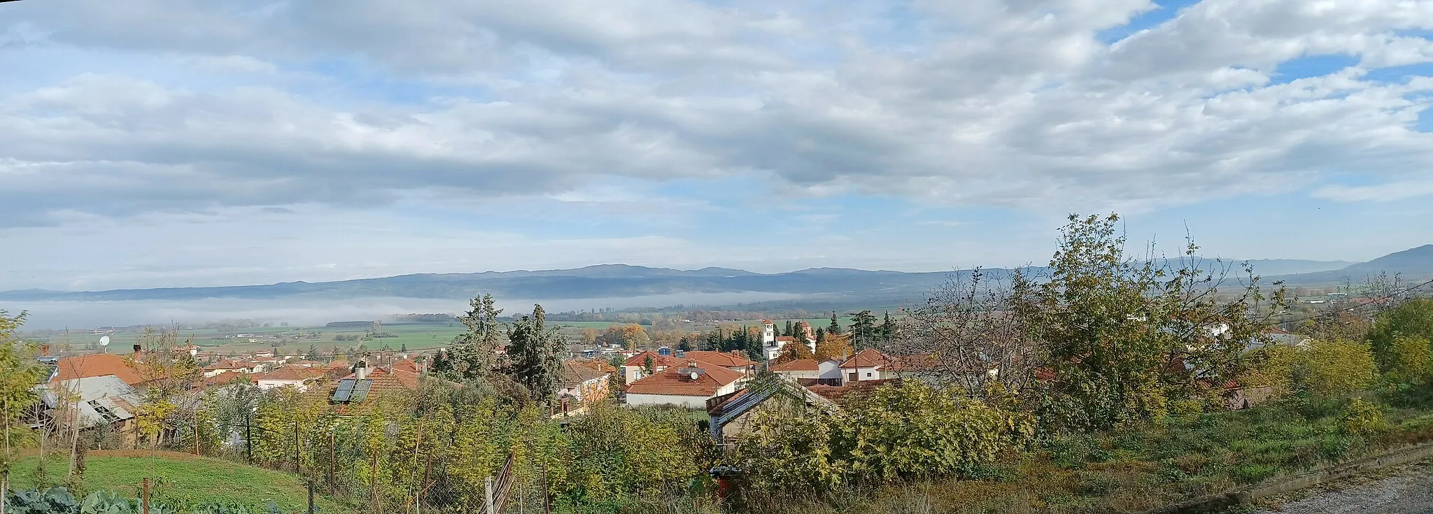 Photo showing: Η θέα από το ψηλότερο σημείο του χωριού, προς το χωριό και το χαμηλό σύνεφο μακρυά στο βάθος.