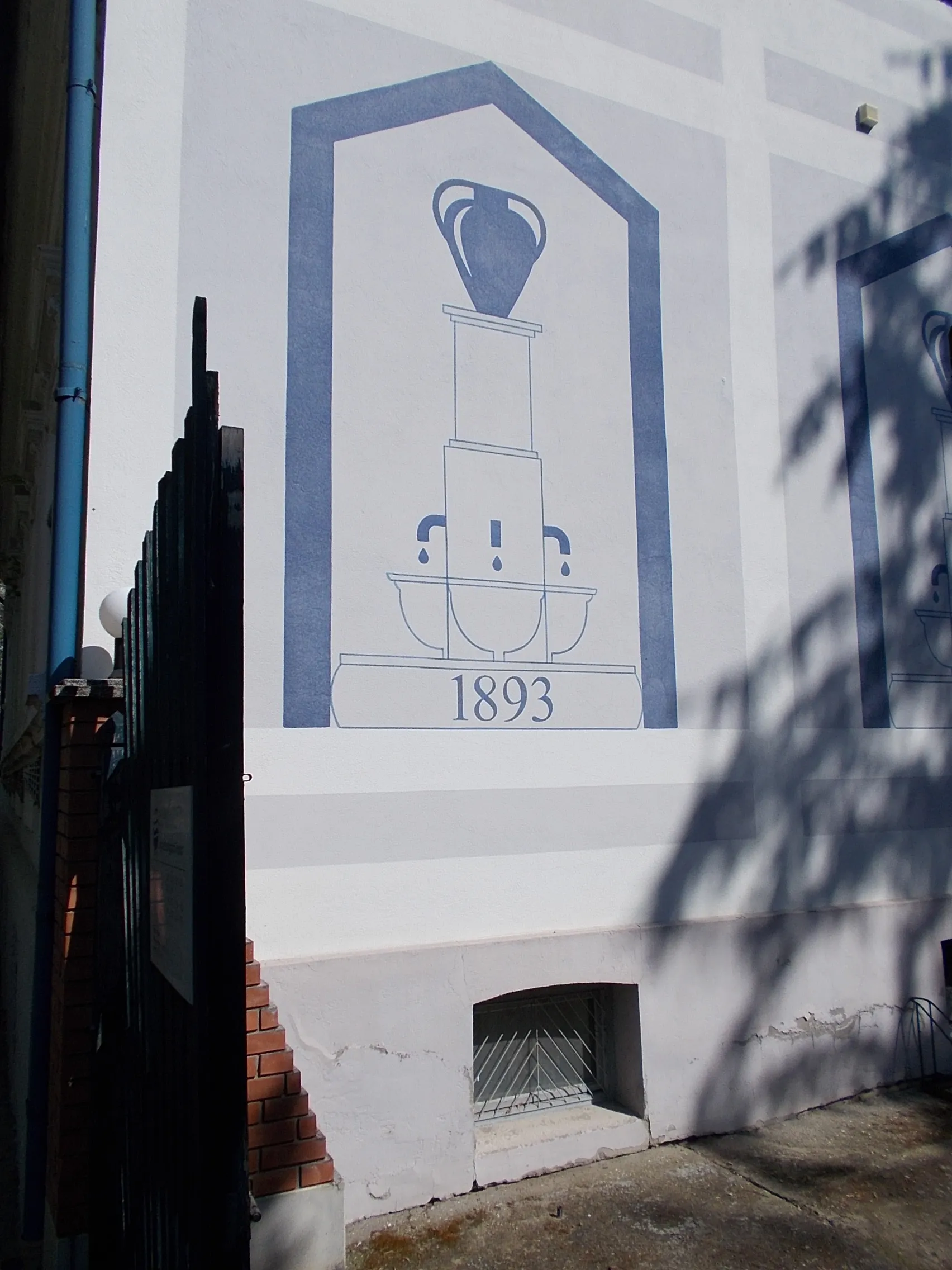 Photo showing: Local grade listed waterwork company office In its fence a pargola with bench and a abstract, onion headed marble fountain by cermics Péter Matl work, 1999 installed. On the building facade a plaque (2007)- 24 Lonovics Avenue (former Bajcsy-Zsilinszky Street), Makó, Csongrád-Csanád County, Hungary.