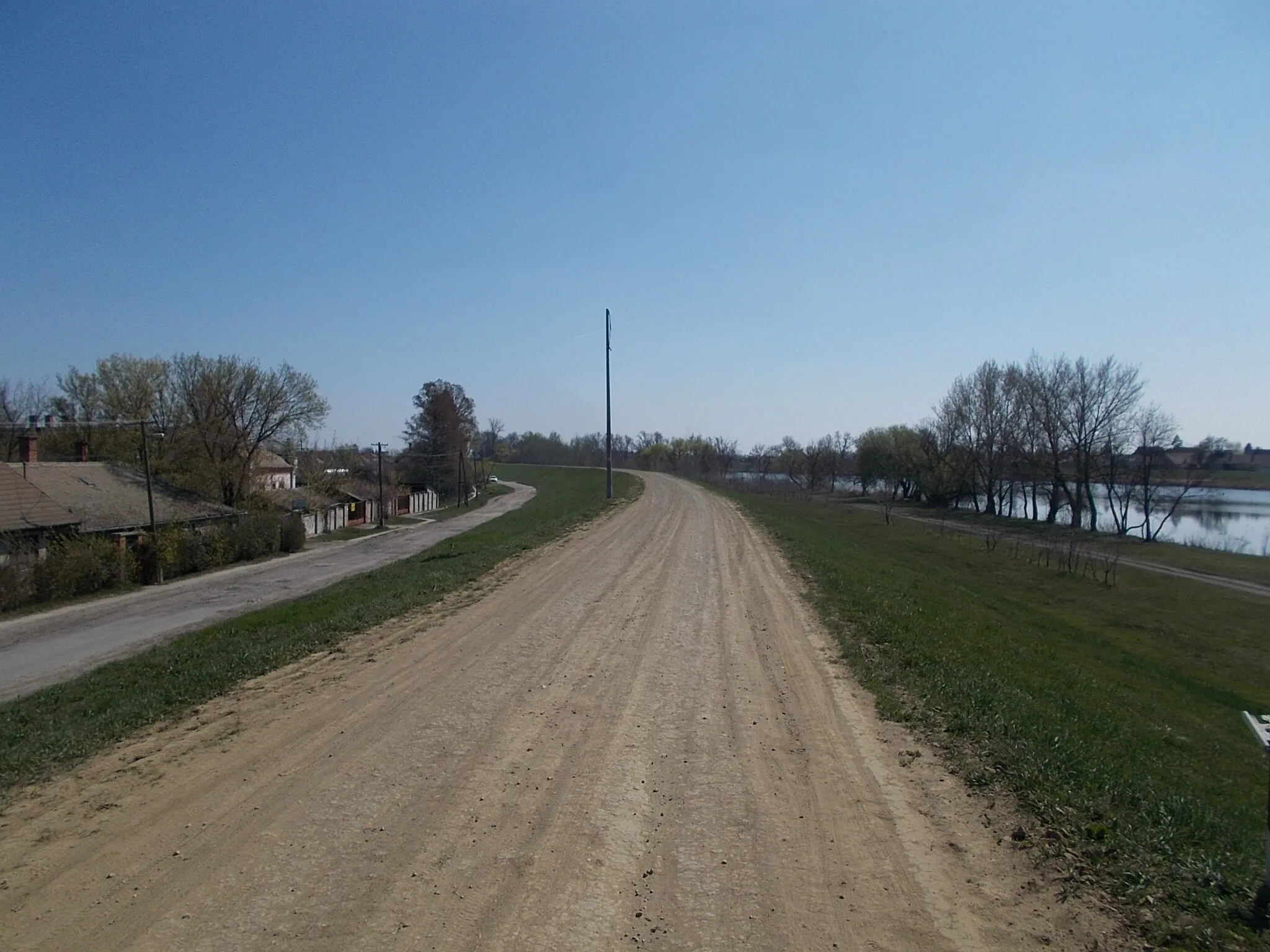 Photo showing: : Vágóhíd street (left) and dirt road on Berettyó dam - Vágóhídikert (~Garden of slaughterhouse) neighborhood, Mezőtúr, Jász-Nagykun-Szolnok County, Hungary.