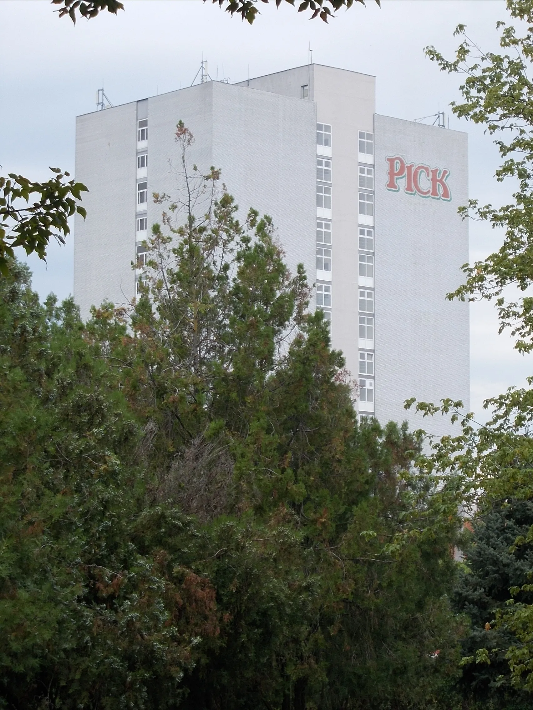 Photo showing: 63 meters high 'rippen' tower building, ensures salami/meat maturation. Part of the Pick Szeged Salami Factory and Meat Factory  viewed from Alsóváros (Lower Town) Cemetery, Alsóváros (Lower Town) neighborough, Szeged, Csongrád-Csanád County, Hungary.