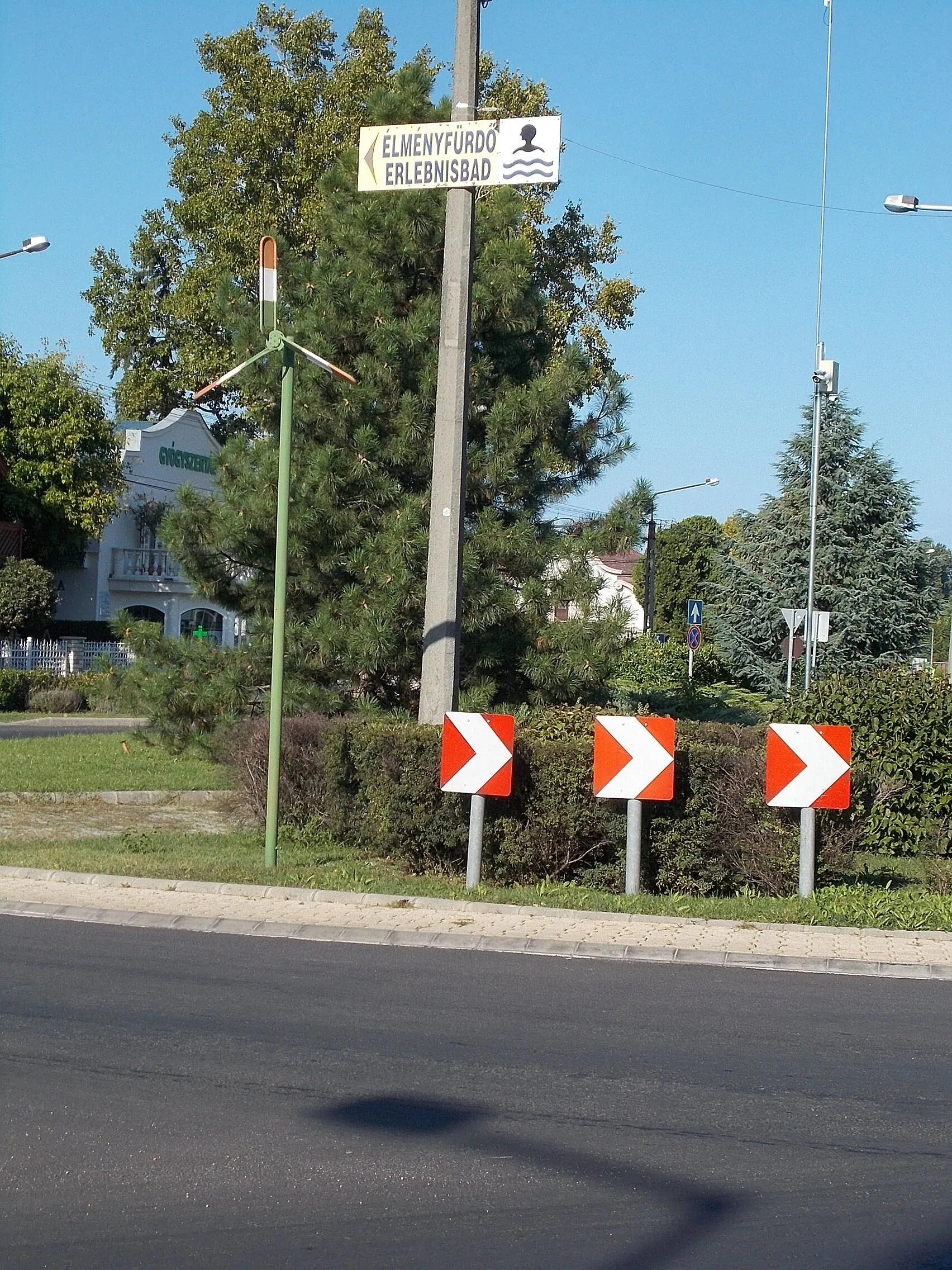 Photo showing: : Propeller painted to National flag colour;  windturbine? at back some kind antenna pole, wheather station? Left back is a pharmacy. Sign of adventure pool by a roundabout of Rákóczi Road (Route 7) & Kossuth Lajos street, Balatonlelle, Somogy County, Hungary.