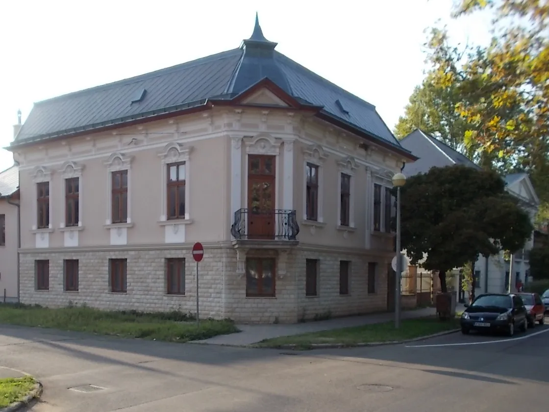 Photo showing: : Listed corner house with a corbel supported 'basket type' wrought iron balcony. Richly decorated with stucco. - 16 Bessenyei Square, Nyíregyháza, Szabolcs-Szatmár-Bereg County, Hungary.