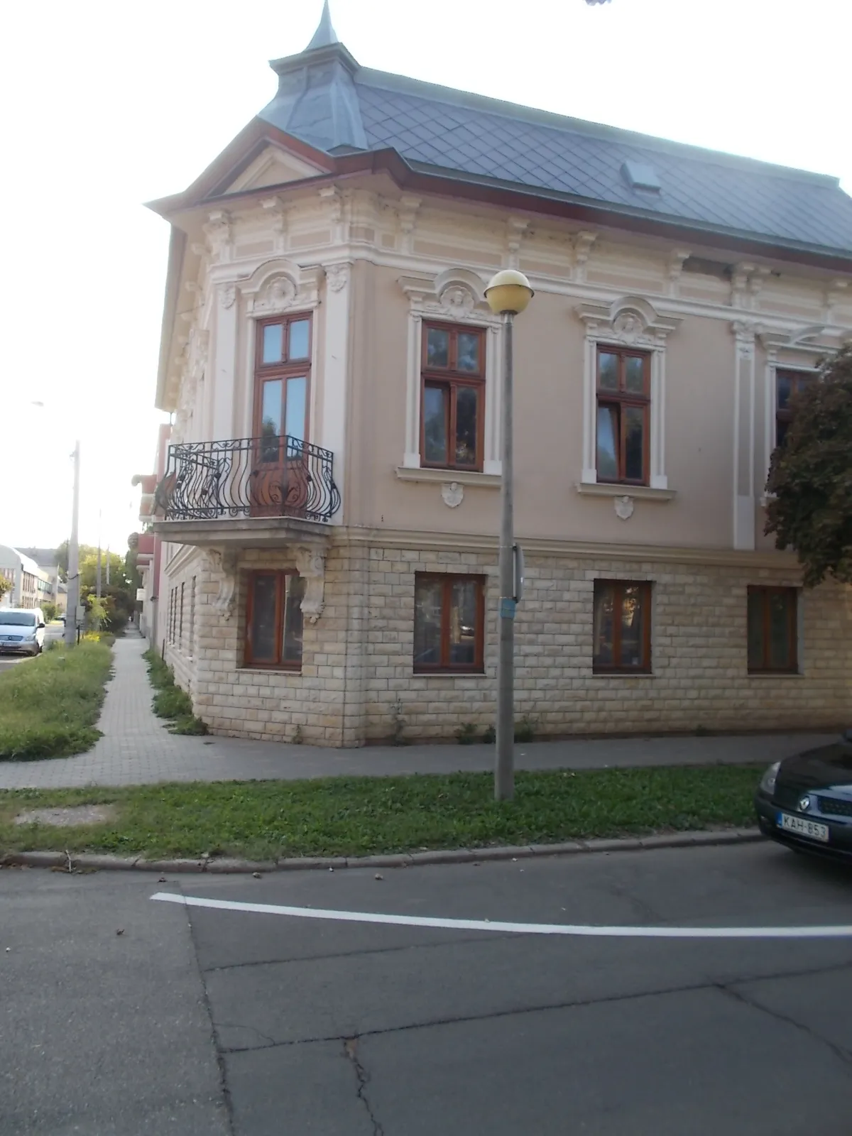 Photo showing: : Listed corner house with a corbel supported 'basket type' wrought iron balcony. Richly decorated with stucco. - 16 Bessenyei Square, Nyíregyháza, Szabolcs-Szatmár-Bereg County, Hungary.