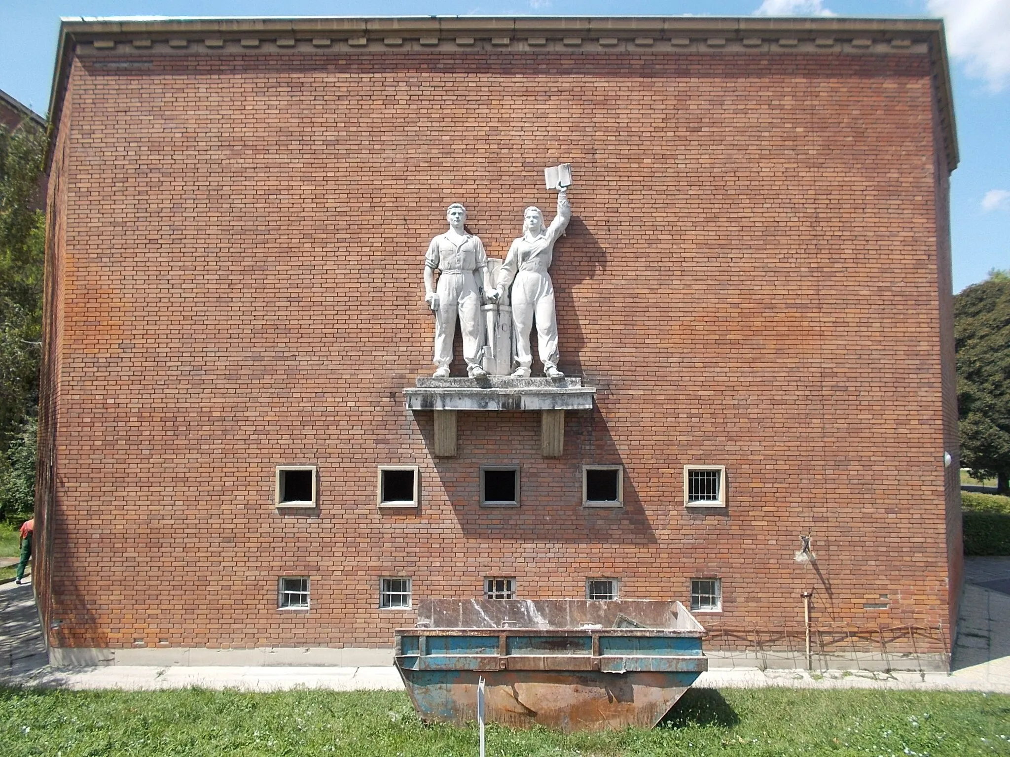 Photo showing: : Built to ~School of Industrial Learners in 1953, planned by Gyula Rimanóczy. Now Győri Technical Vocational Training Center  Lukács Sándor Mechatronic and Mechanical Elementary School, Secondary School and its Student Housing. On its facade a worker couple near two meter high limestone socialist realism statues by Gyula Palotai, 1951 - Gyárváros neighborhood, Győr, Győr-Moson-Sopron County, Hungary.