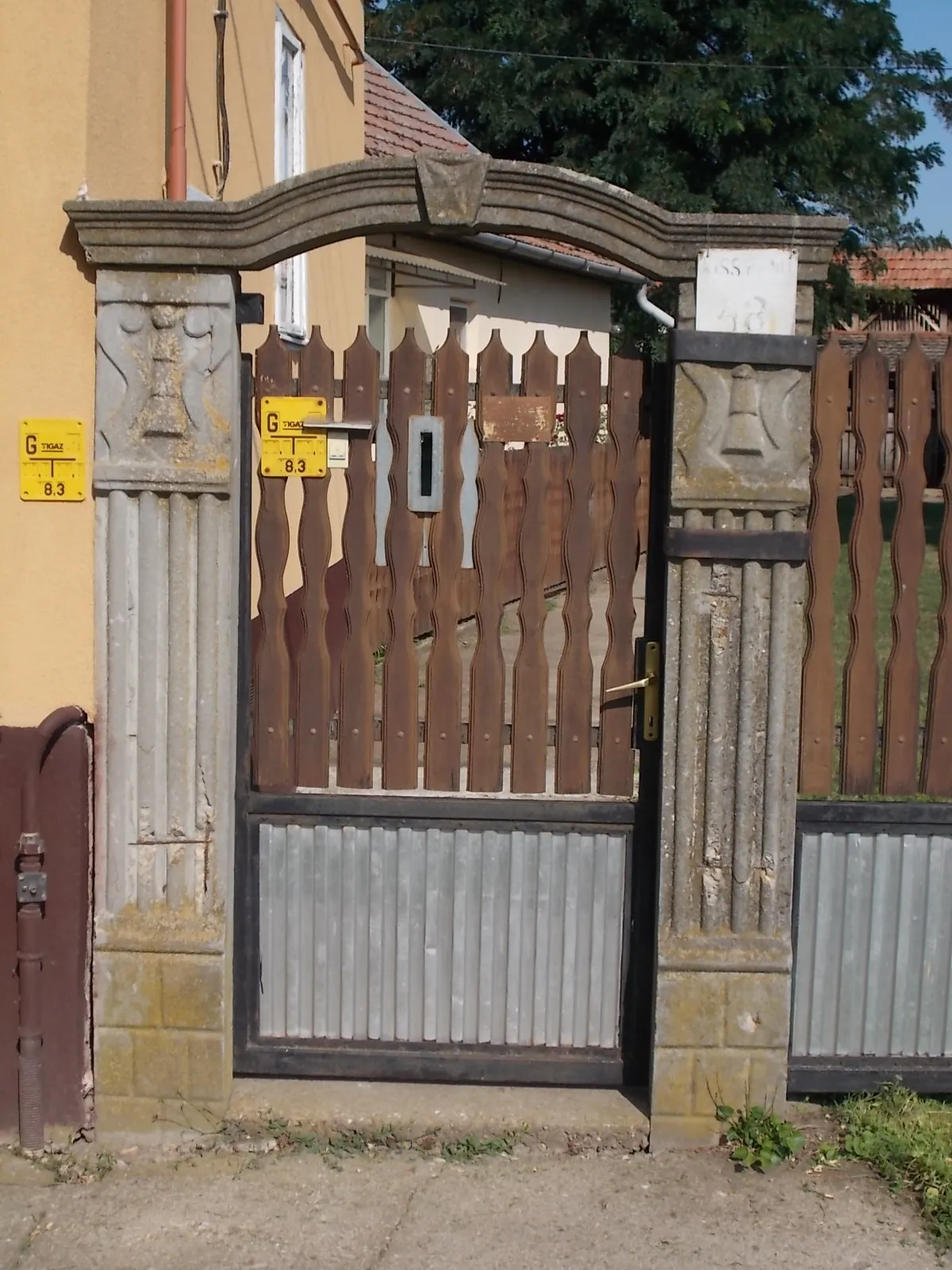 Photo showing: : Street door gate. Stone-concrete framed wooden metall. - 48 Kiss Ernő Street, Hajdúnánás, Hajdú-Bihar County, Hungary.