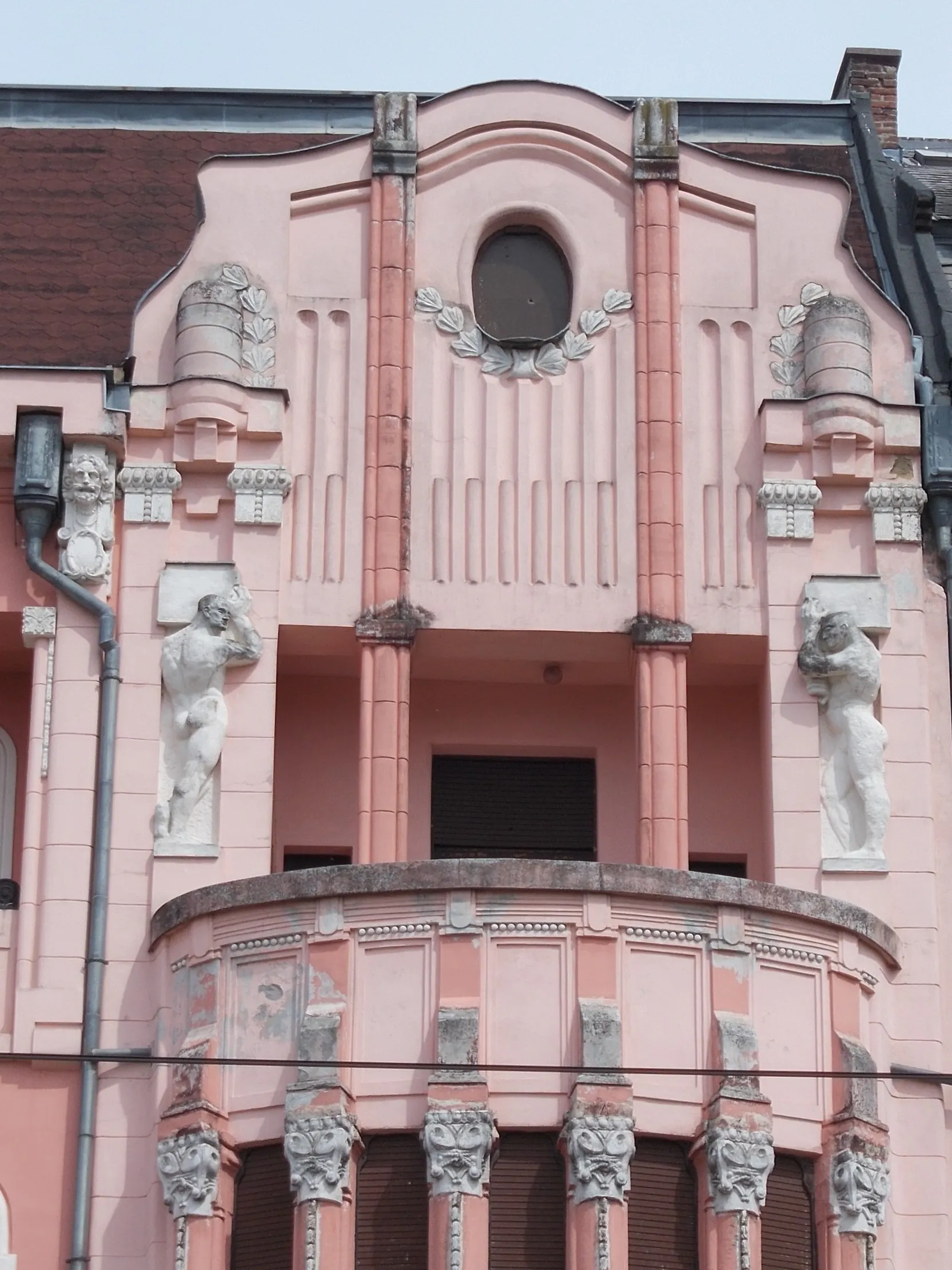 Photo showing: HQ of the former Debrecen First Savings Bank. Buil in 1912 Planned by Kálmán Rimanóczy Jr.. Construction contractors: István Tóth, Szilágyi and Pavlovits. Facade allegorical sculptures related to agriculture, industry and commerce  and the nude male stuccos are Sándor Somogyi works). There is couple bronze bird statues (Turul?). Inside coulmn capatáls made from Zsolnay ceramic. In addition to the premises of the Savings Bank, there were shops on the ground floor, on the Kossuth street side there were originally an officer's casino, in the cellar there was a beer hall and restaurant, on the floors there were seventeen luxury rental apartments. - 22-24 Piac Street, Inner City,Debrecen, Hajdú-Bihar County, Hungary.