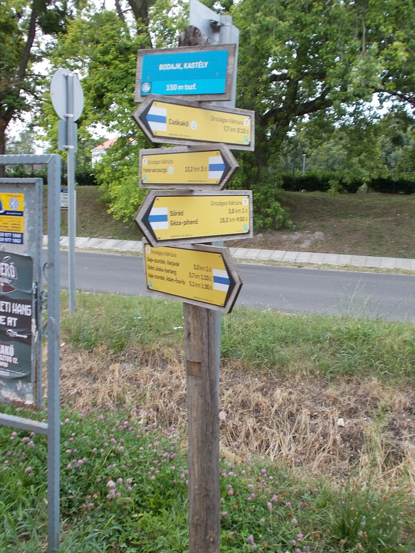 Photo showing: National Blue Circle fingerpost - part of National Blue Trail and Way of Mary (Bodajk– Majkpuszta section) trail, before #76 Petőfi Sándor Street (Route 8204), Bodajk, Fejér County, Hungary.