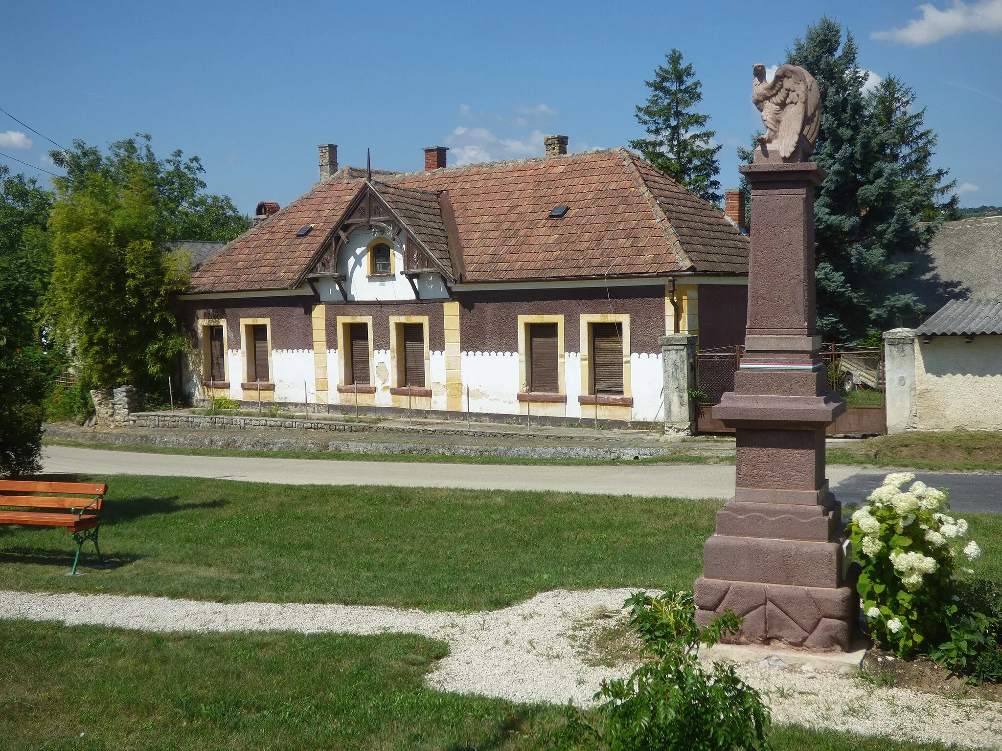 Photo showing: Nagypécsely központja a I. világháborús hősi emlékművel (Avatás 1931, vörös homokkőből készült, fehér márványtáblákkal kiegészítve. A tetején álló turul, műkőből készült, valószínűleg utólag kerülhetett rá.)[1]