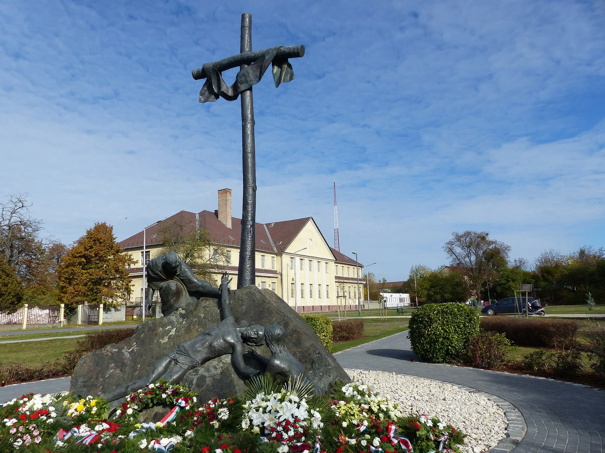 Photo showing: 1956-os emlékmű. A felvétel 2016. október 31-én készült Mosonmagyaróváron, a Gyász téren. 1956 október 26-án az ÁVH határőr laktanya előtti tömegbe lőttek az ÁVH-sok. Az ismételt sortűz a menekülők hátát érte. A tömeggyilkosságban a visszaemlékezők szerint 104-en haltak meg. A laktanya parancsnoka Dudás István (Abádszalók 1924 augusztus 20 - Kiskunhalas, 2002 június 28) volt.  Források: Böröndi Lajos: Dokumentumok 1956 - Mosonmagyaróvár Integratio, Bécs, 2006. http://www.mosonvarmegye.eoldal.hu/cikkek/1956---mosonmagyarovar/sortuz-es-megtorlas.html (hozzáférés: 2016.10.31).