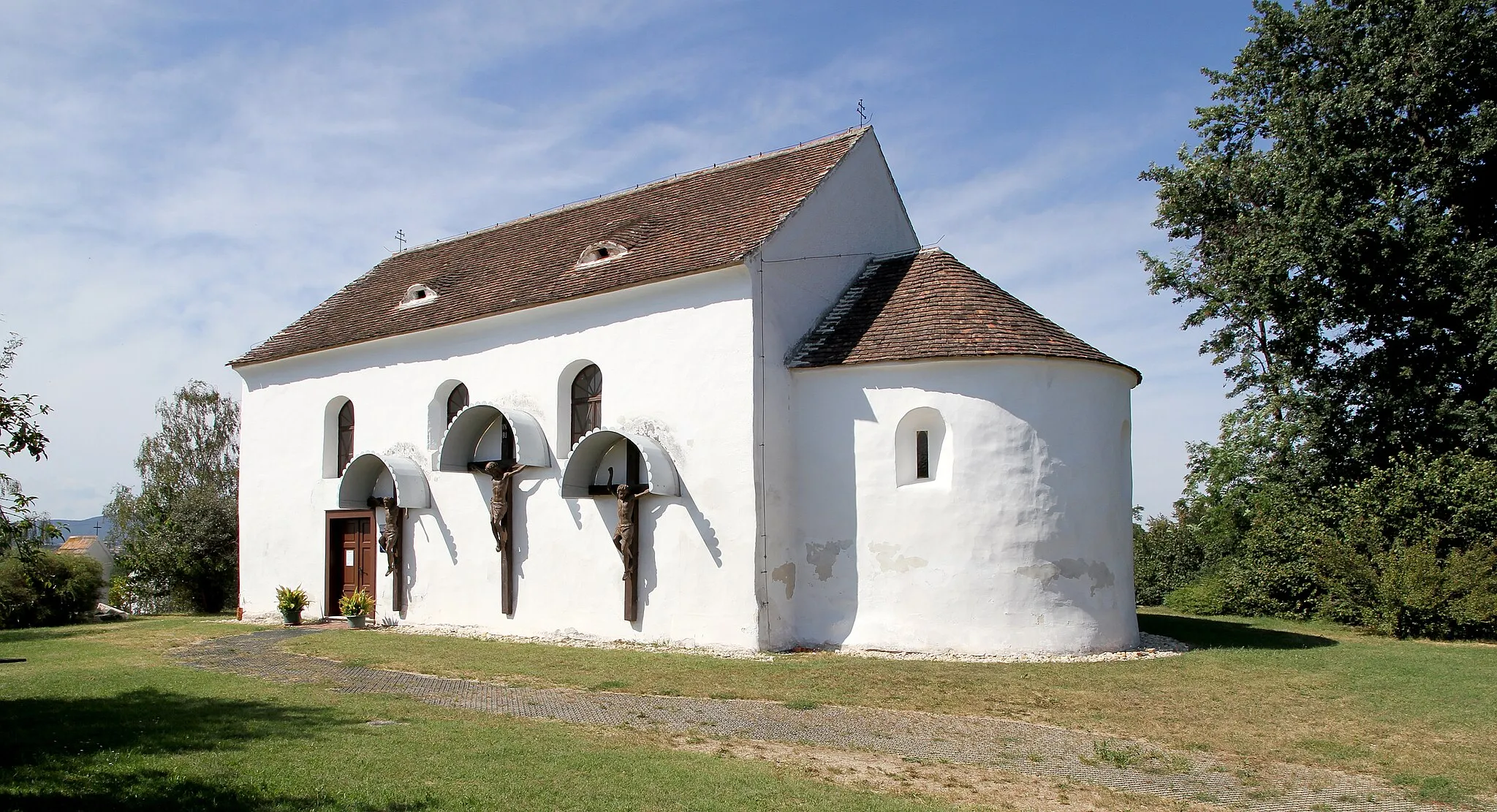 Photo showing: Die röm.-kath. Bergkirche von Stoob. Ein romanischer Rechteckbau aus dem 13. Jahrhundert mit eingezogener Halbkreisapsis, in der Wandmalereireste aus den Jahren um 1220/1230 freigelegt wurden, die Christus und die 12 Apostel darstellen. An der südlichen Außenwand befindet sich eine Kreuzigungsgruppe (Gekreuzigter und die zwei Schächer) aus Holz; eine Grödentaler Holzschnitzarbeit aus dem Jahr 1891.