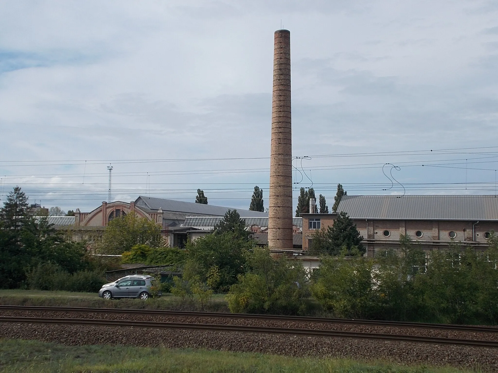 Photo showing: : Rail Vehicle Repair factory chimney from Klapka Street. - Állomás Promenade, Dunakeszi, Pest County, Hungary.