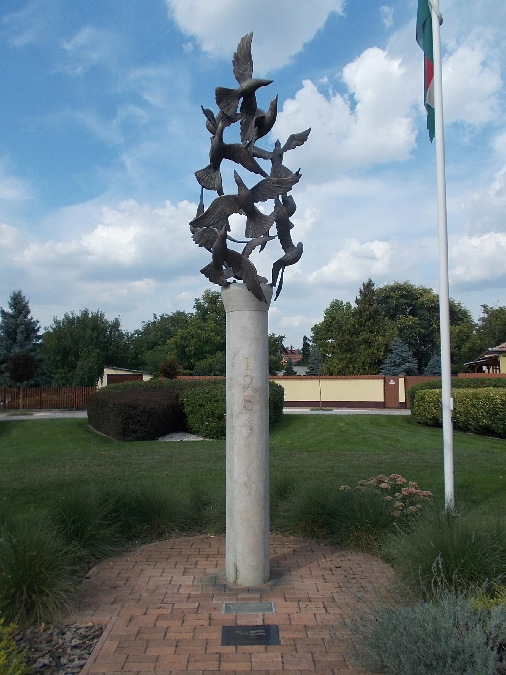 Photo showing: Memorial column of the 1956 Hungarian Revolution by Károly Barth (2006 works, 2.5-3 meters high limestone column, nine 'flying' bronze birds). There are ground based plaques at the memorial - in a Park at Szent István Street and Somogyi Béla Street intersection, /Szent István Square other name Templom Square/, Gyálliget neighborhood, Gyál, Pest County, Hungary.